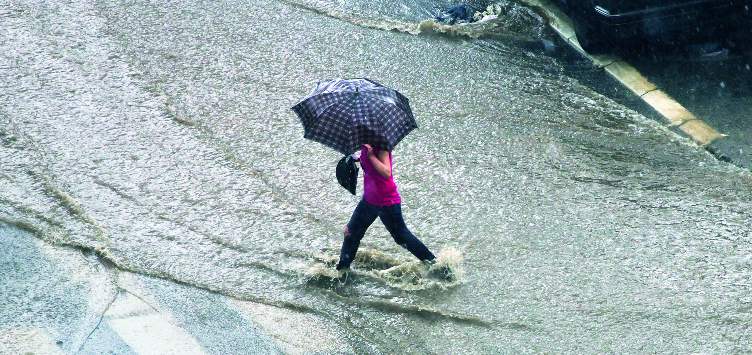Woman with umbrella crossing flooded street