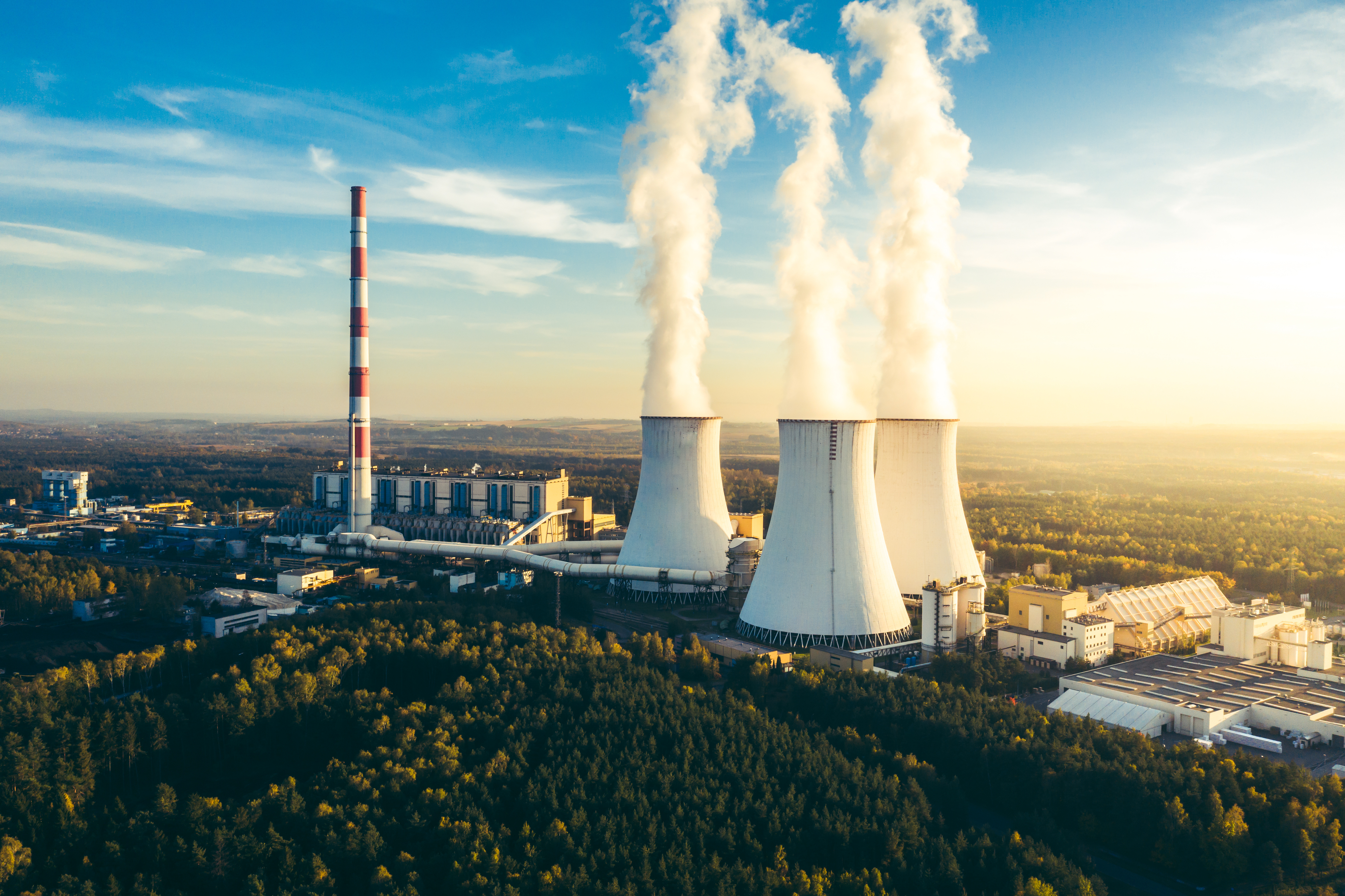 Industrial complex at sunset, illustrating corporate emissions measurement, GHG reporting, and verified decarbonisation strategies for hard-to-abate sectors