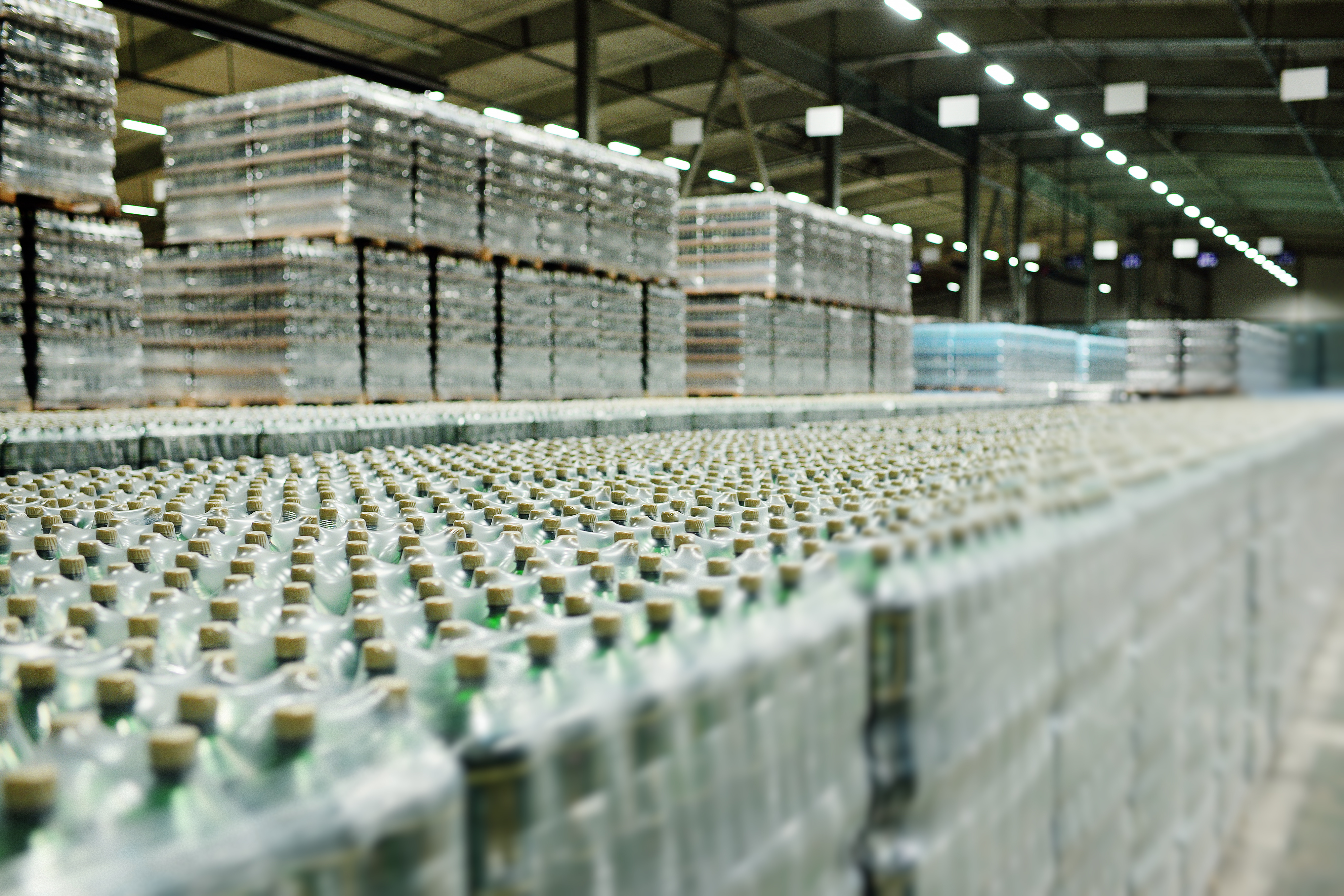Rows of packaged beverage bottles in a large industrial warehouse, illustrating supply chain transparency and social compliance auditing