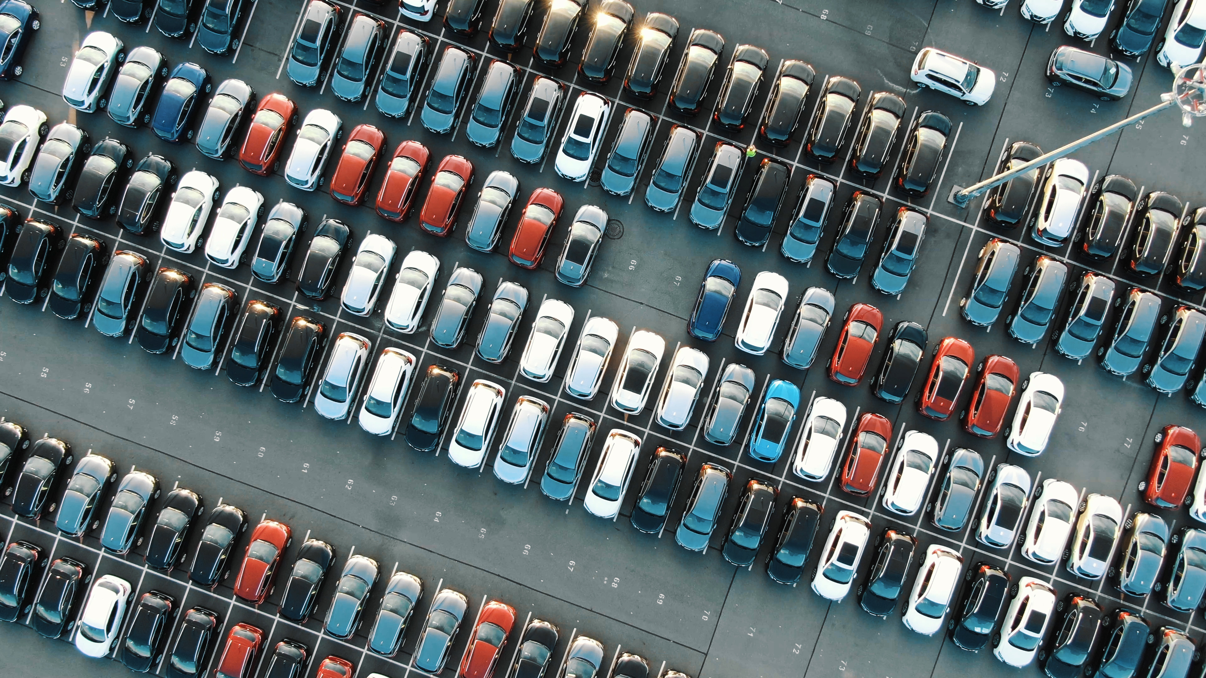 Aerial view of a large vehicle parking lot illustrating market comparison and benchmarking across the automotive industry
