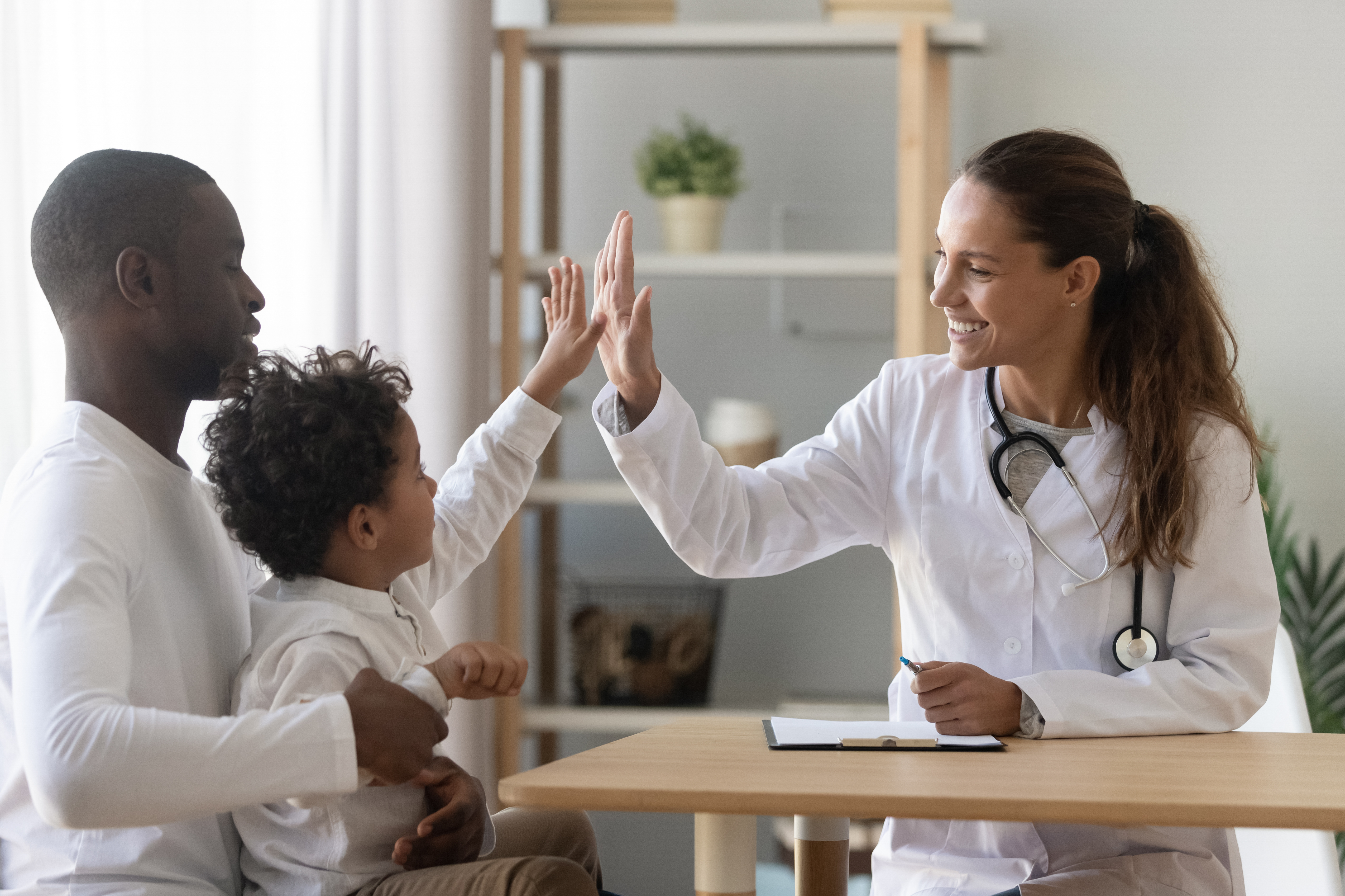 Clinician engaging with a child using a spine model during an orthopaedic consultation, representing evidence-based paediatric spine assessment