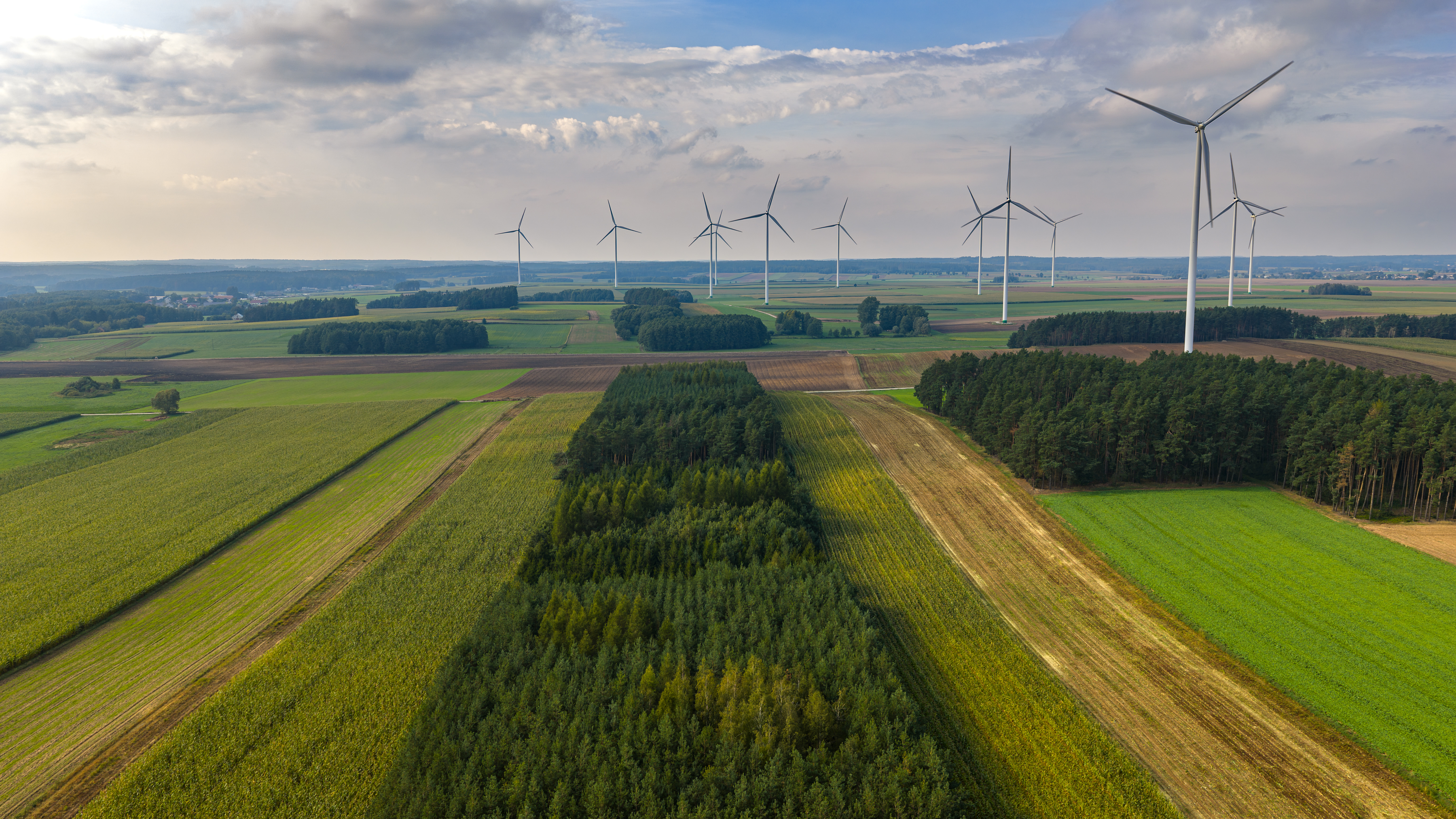 Renewable energy wind turbines operating above agricultural fields, representing sustainable finance and green investment frameworks