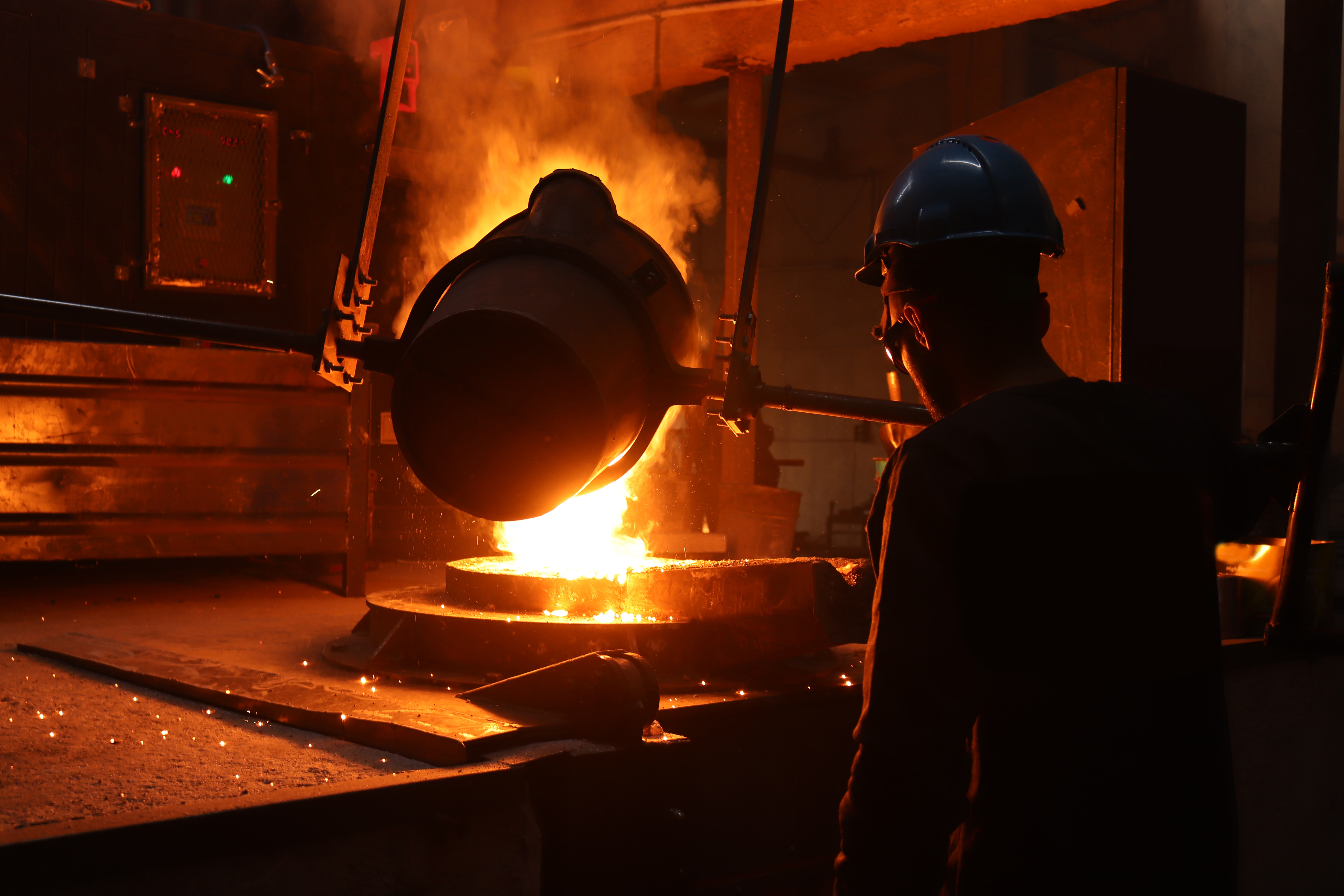 Worker operating equipment in a steel plant, illustrating emissions-intensive processes and the importance of validated and verified carbon reduction outcomes.