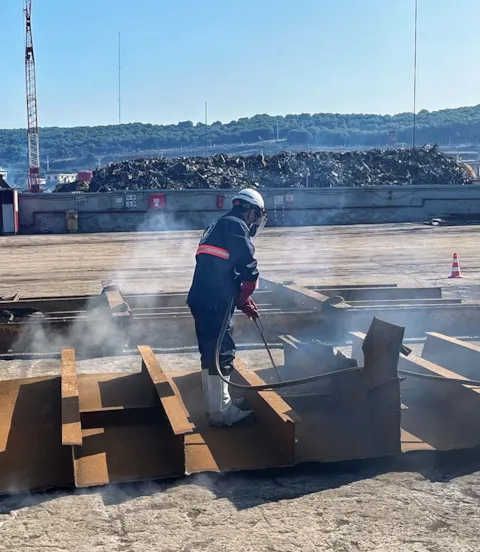 Worker dismantles ship parts