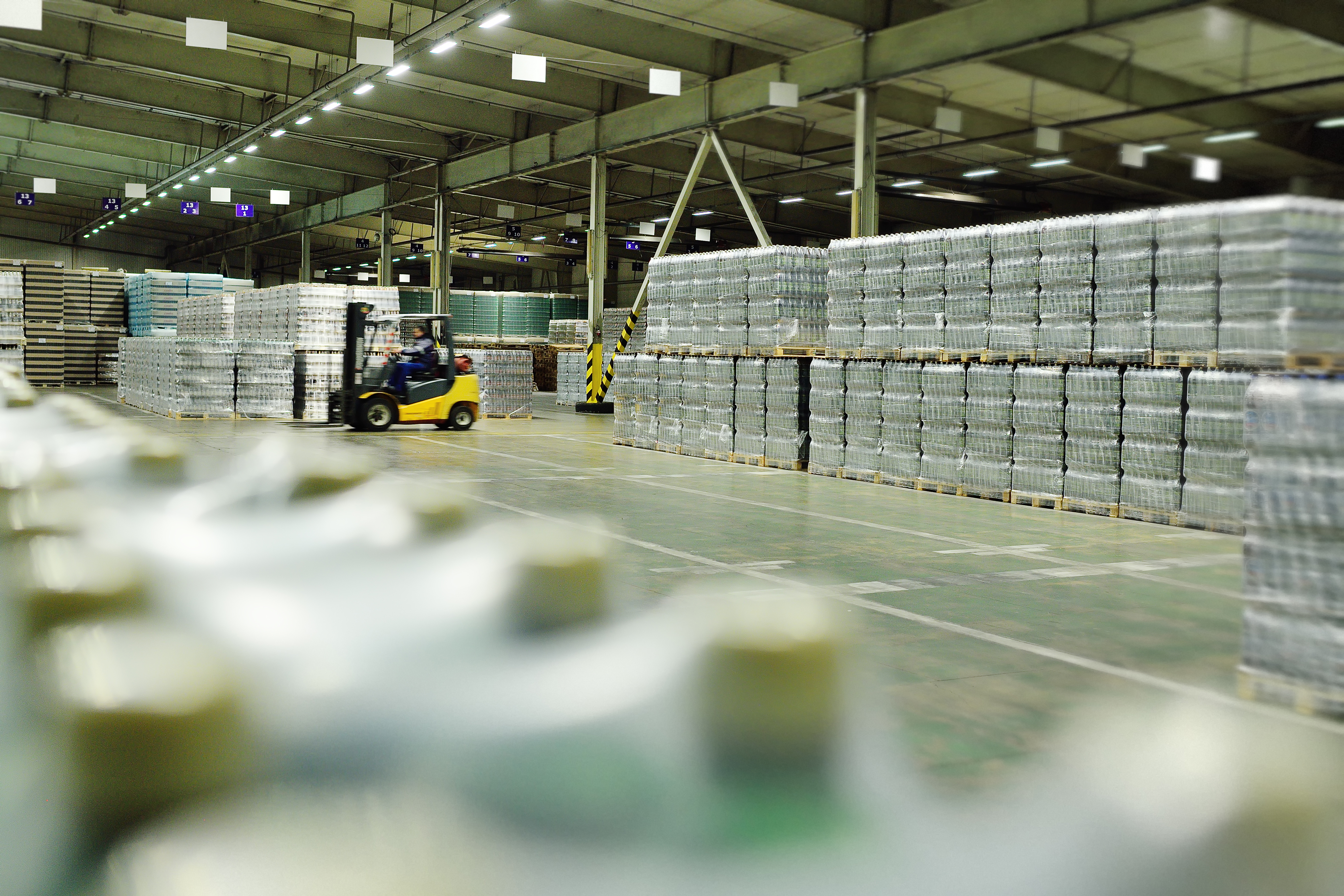 Worker moving pallets inside a distribution warehouse, representing storage, handling, and operational compliance.