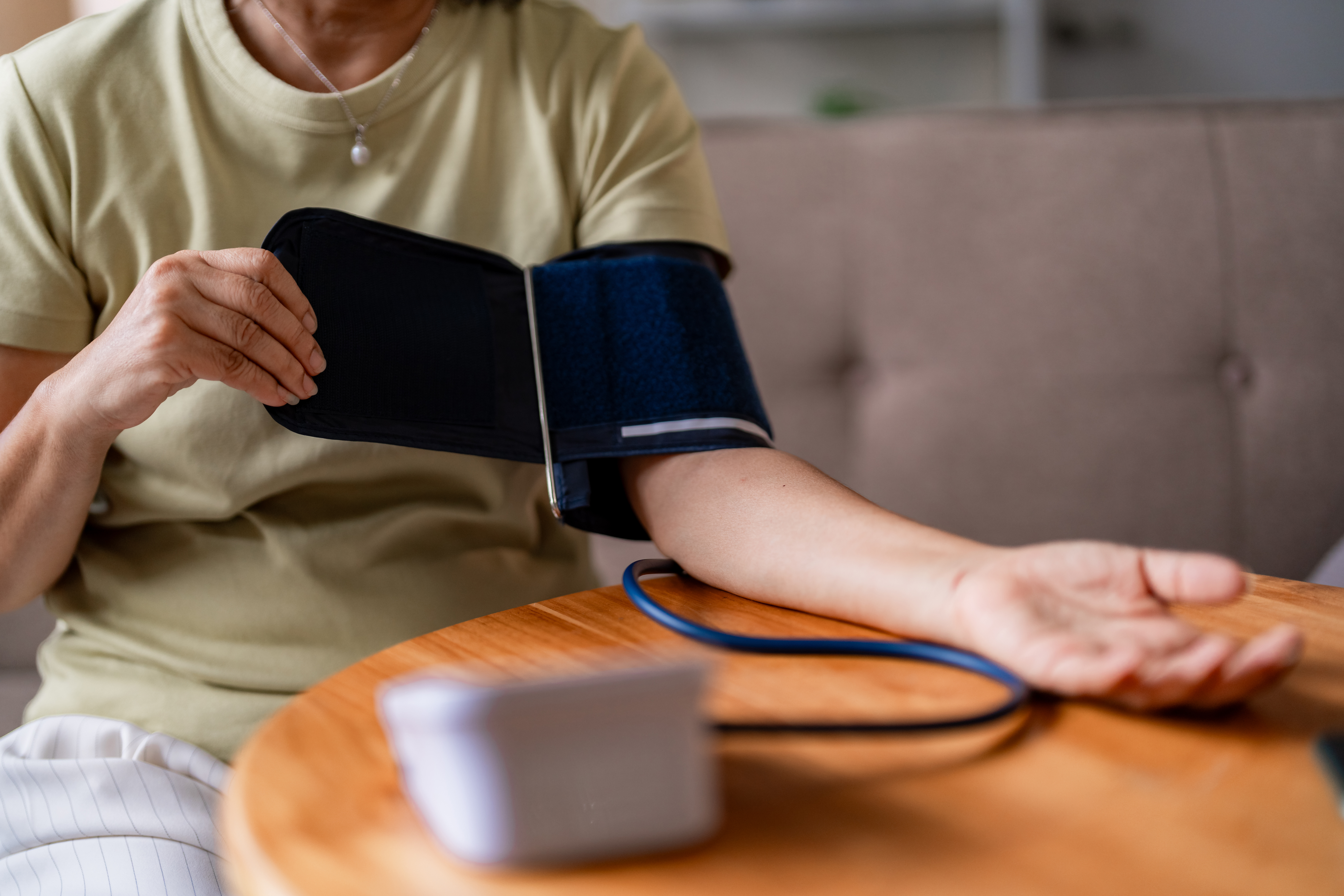 Person measuring blood pressure at home using a digital monitor, representing medical device safety, performance verification, and MDR conformity requirements