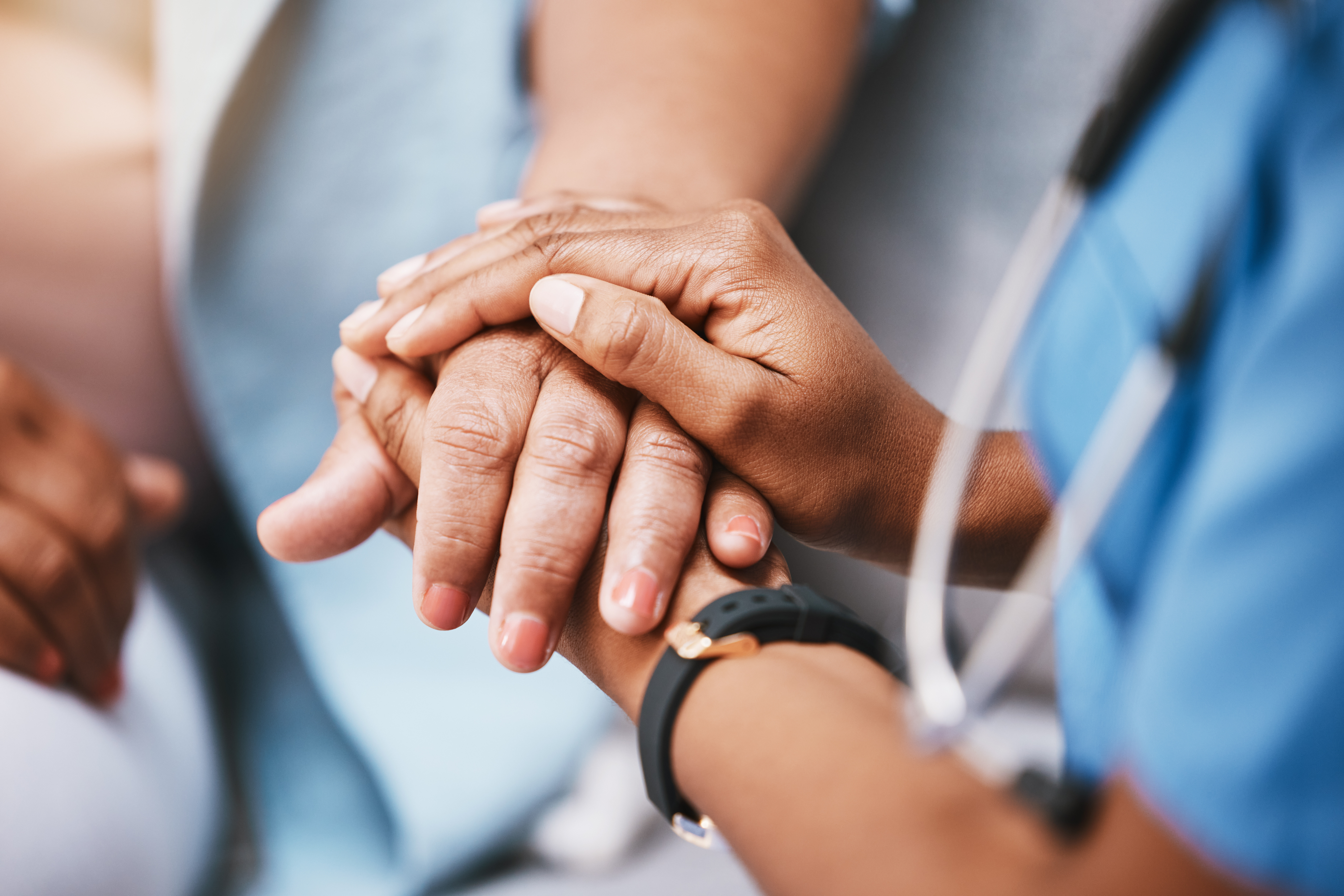 Clinician offering supportive hand to a patient, symbolizing trust, safety, and the importance of secure digital care environments enabled by DNV’s healthcare cybersecurity certification