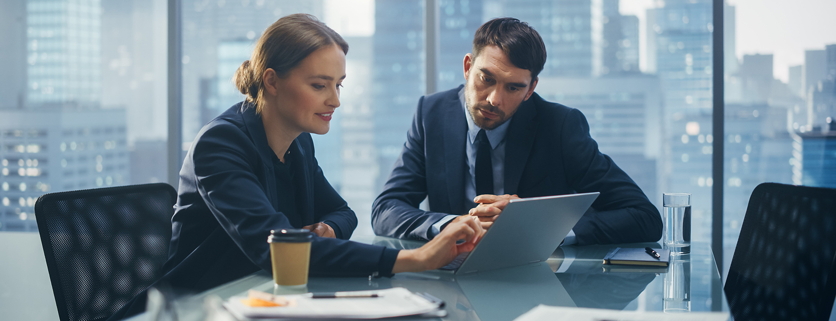 Two people in a meeting studying data on a laptop