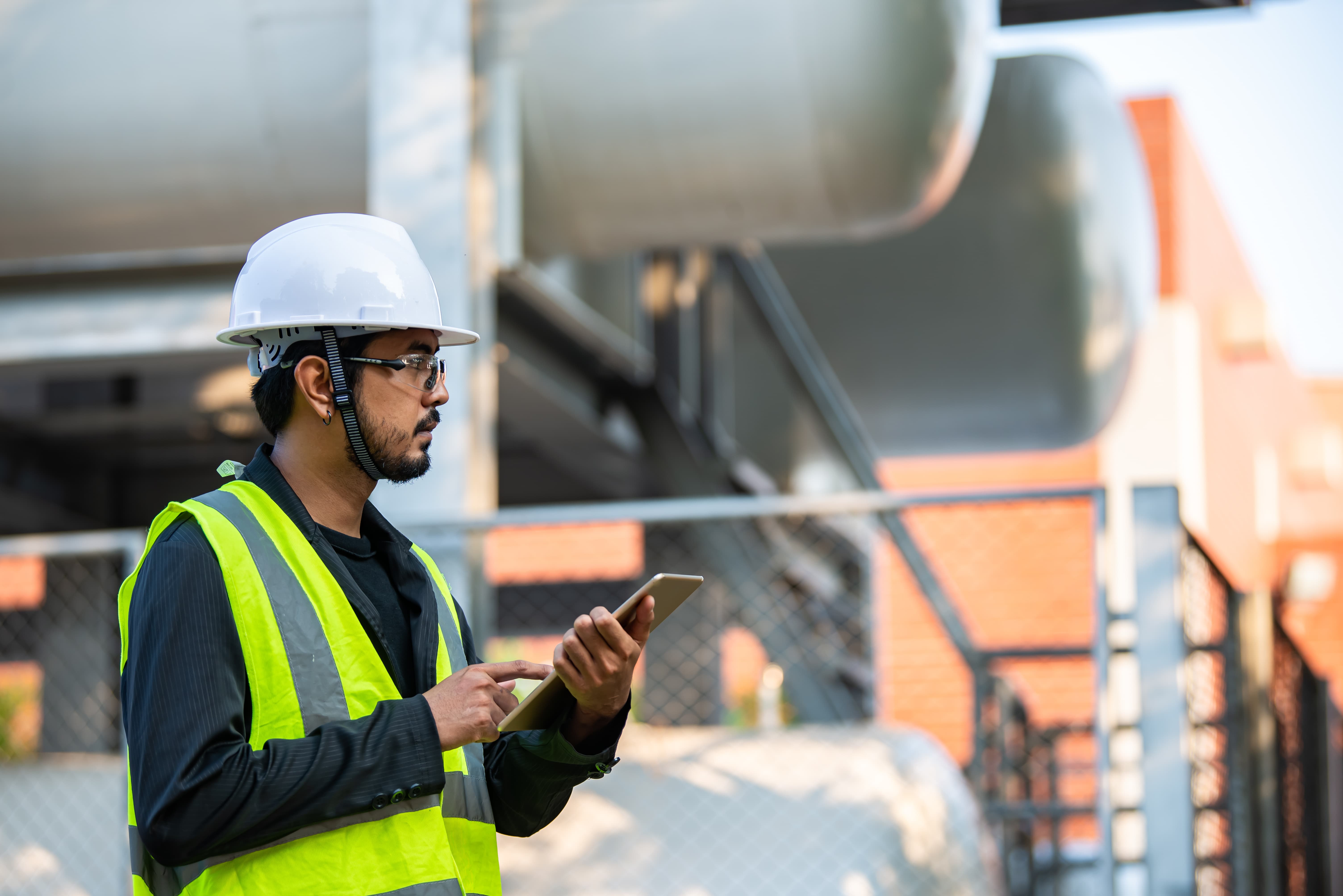 worker on tablet with hard hat and high vis jacket