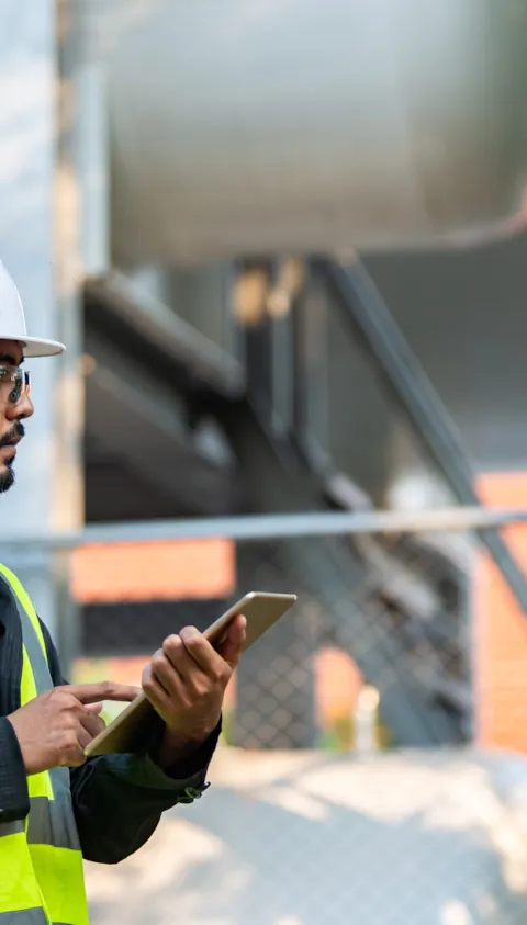 worker on tablet with hard hat and high vis jacket