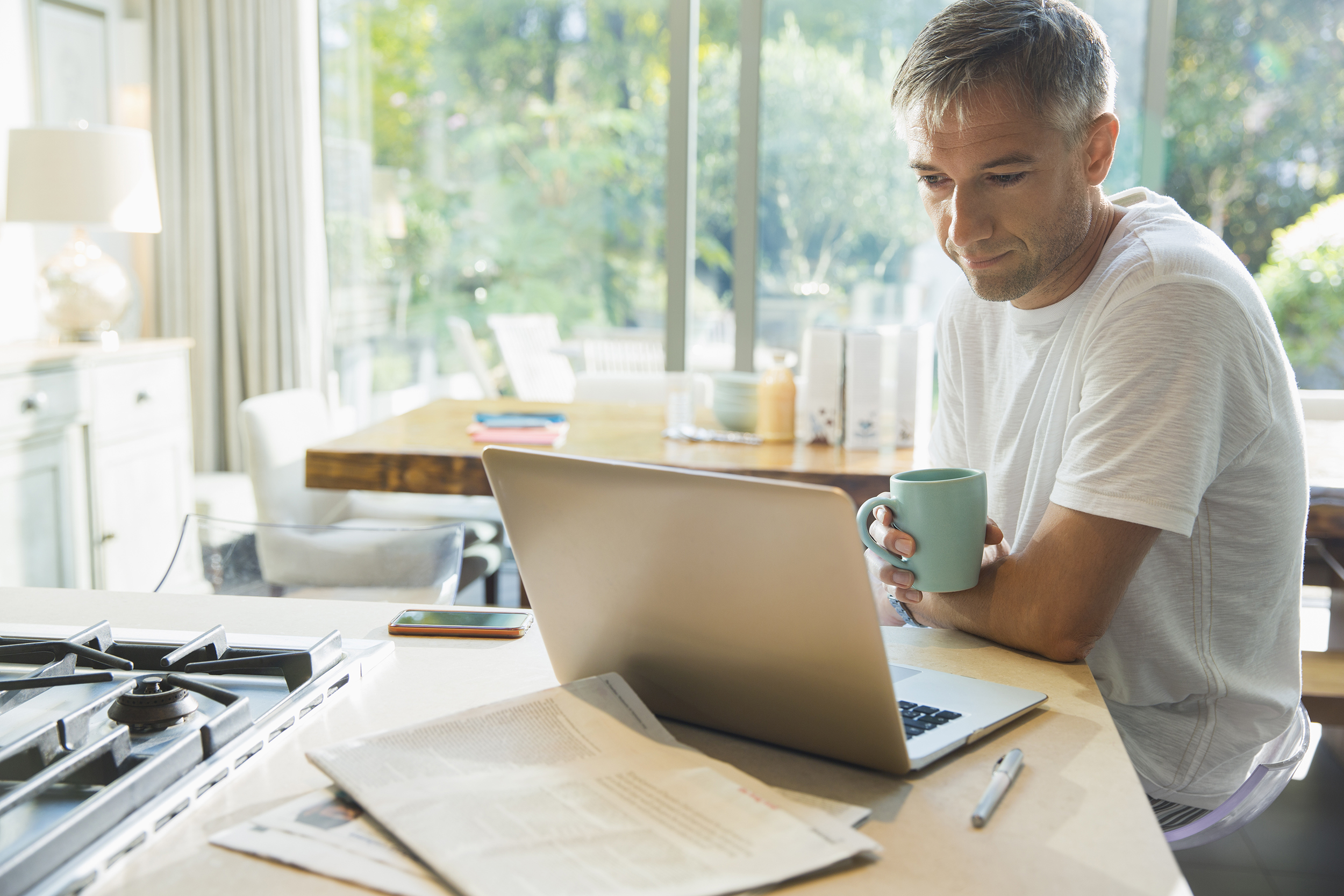 Man drinking coffee and working on laptop