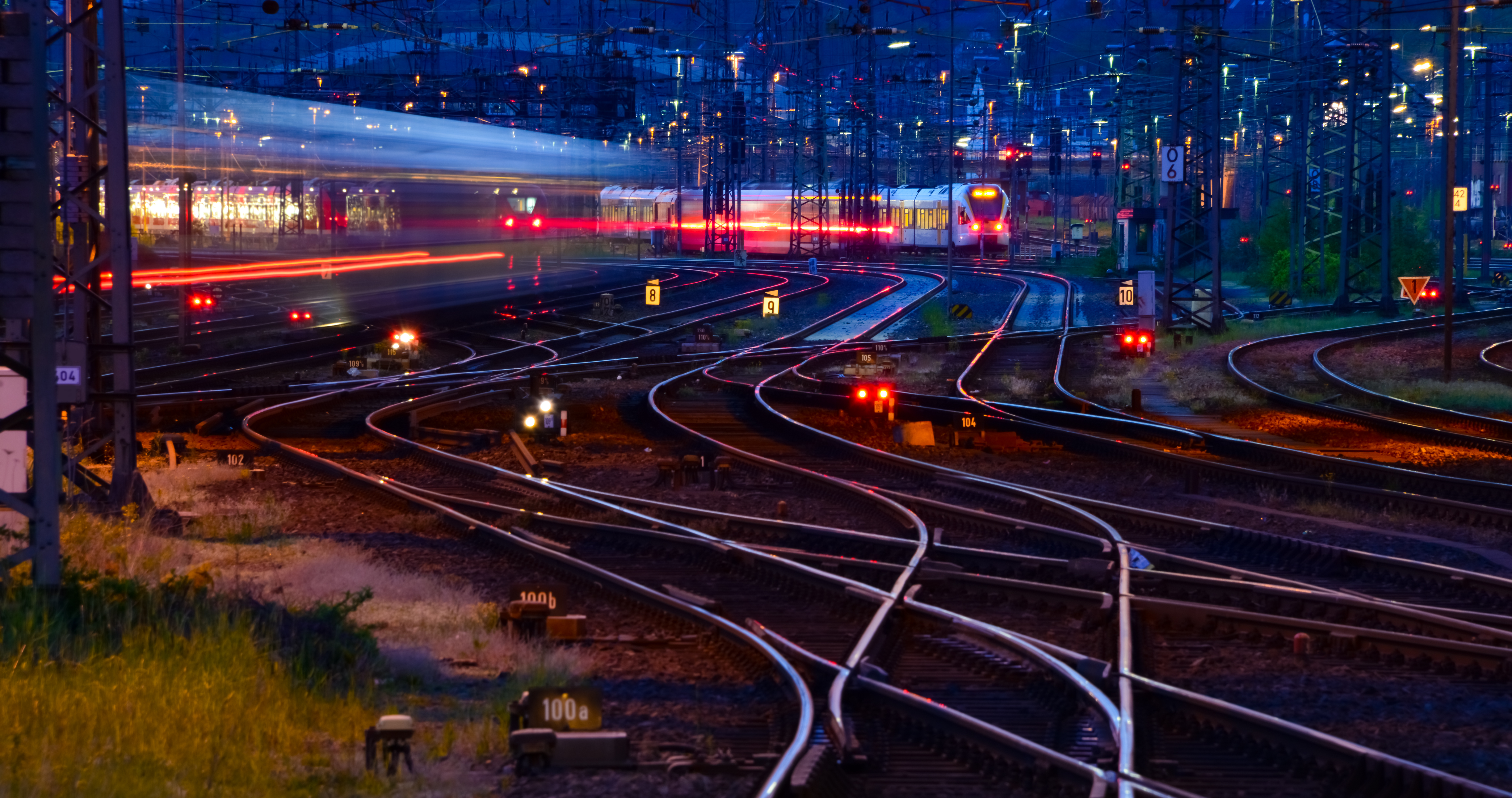 Nighttime rail yard with illuminated tracks and trains, symbolizing cybersecurity and compliance across complex rail systems