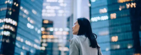 Woman standing against contemporary corporate skyscrapers