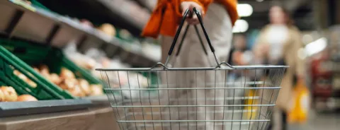 Woman standing next to product aisle and choosing food in the store