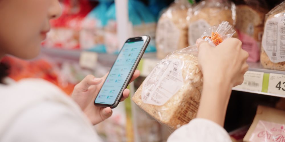 Woman scanning a product with a smartphone in a retail environment, symbolizing supply chain transparency and product traceability