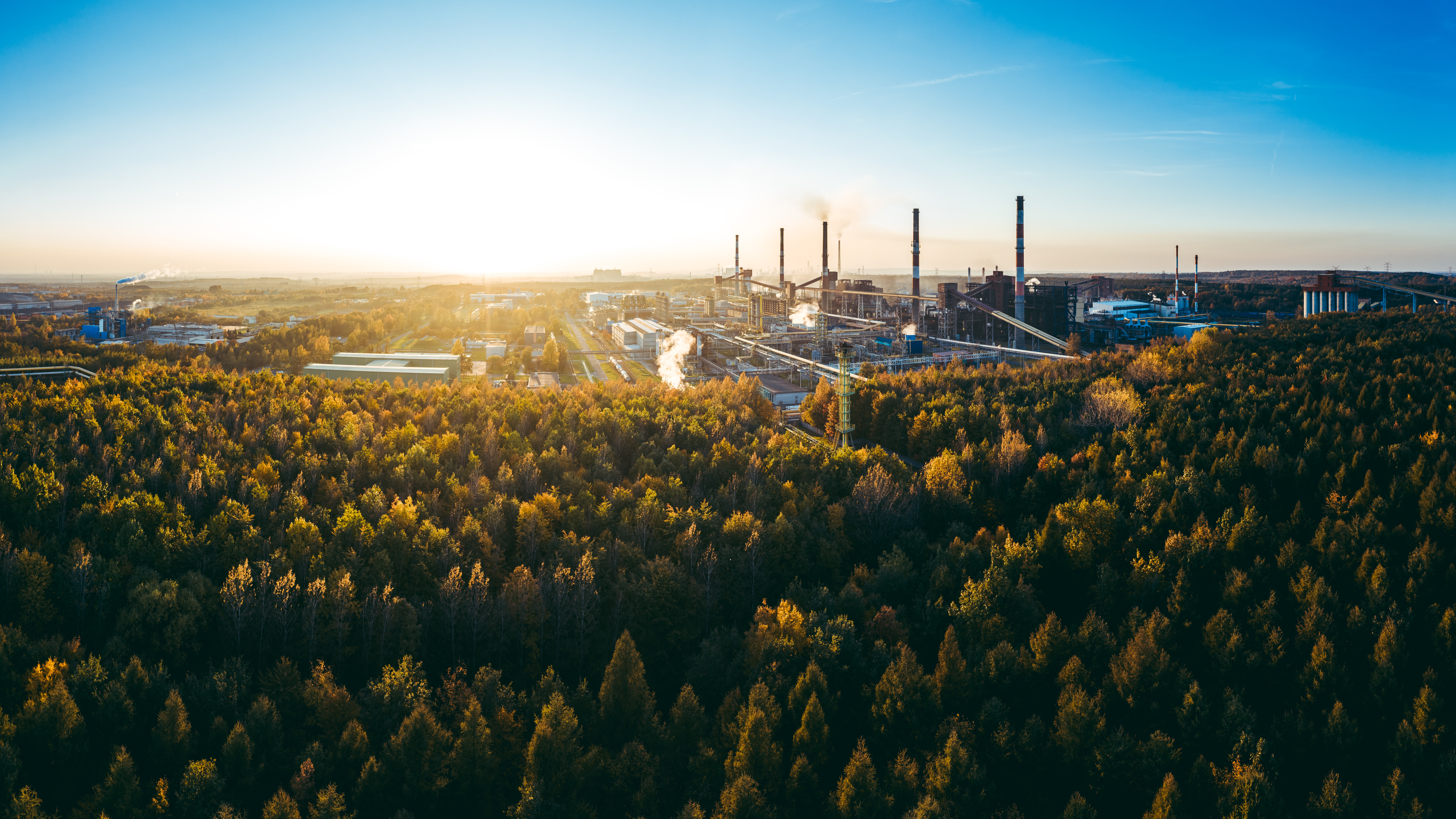 Aerial view of an industrial facility surrounded by forest at sunrise, representing credible carbon credit validation and verified emission reductions.