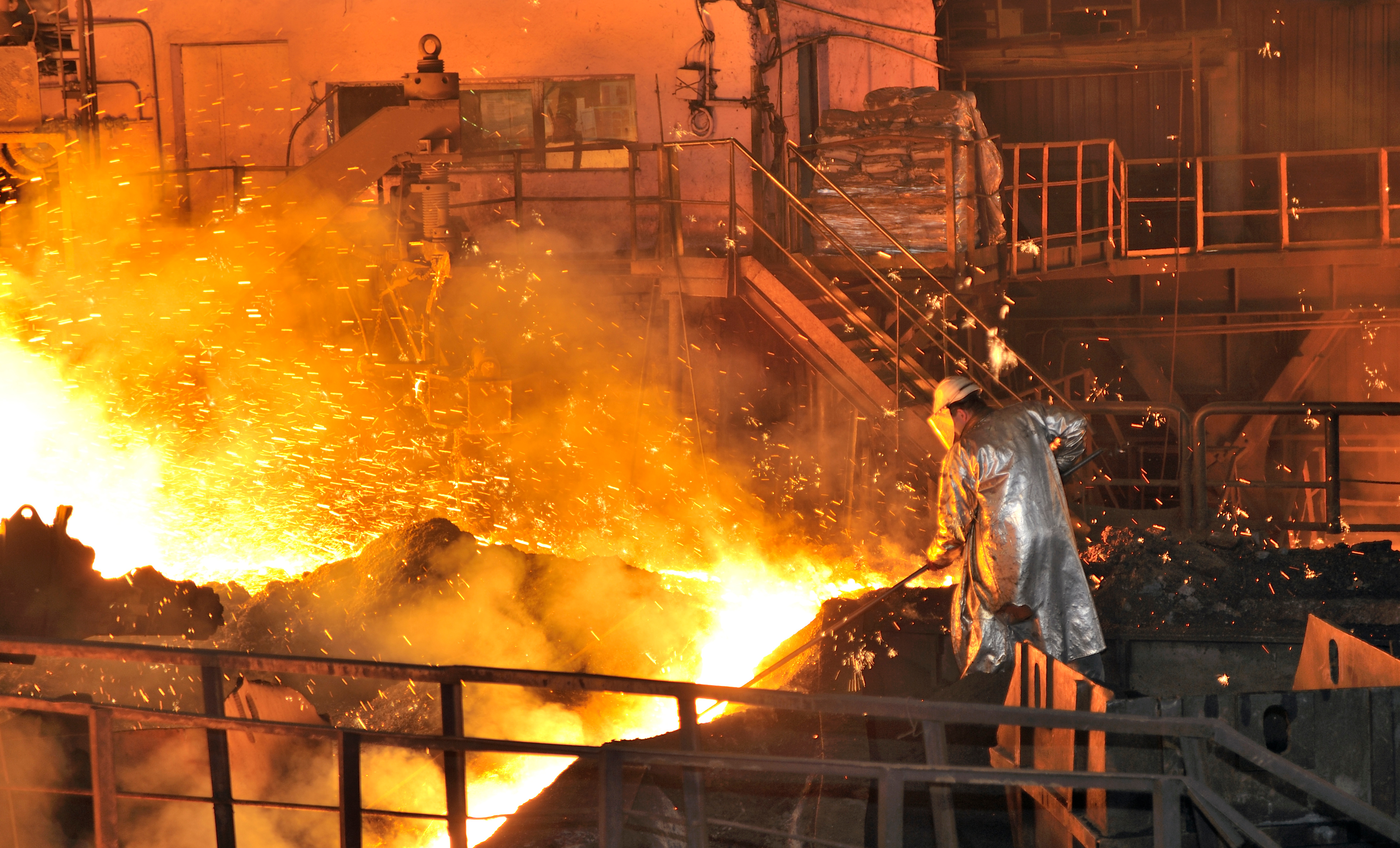 Steel production worker managing molten metal under intense heat