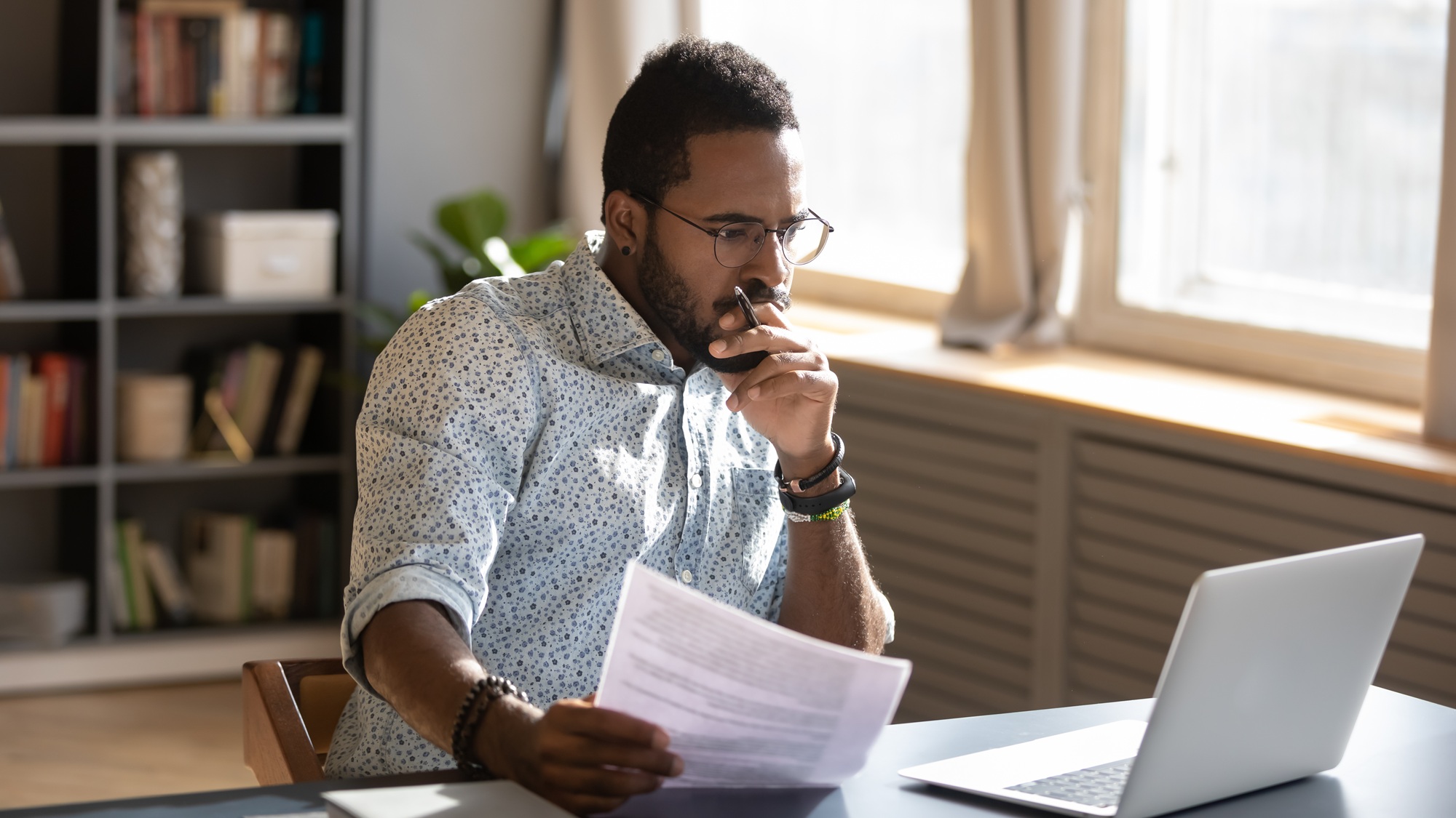 Man reviewing documents, sitting in front of a computer