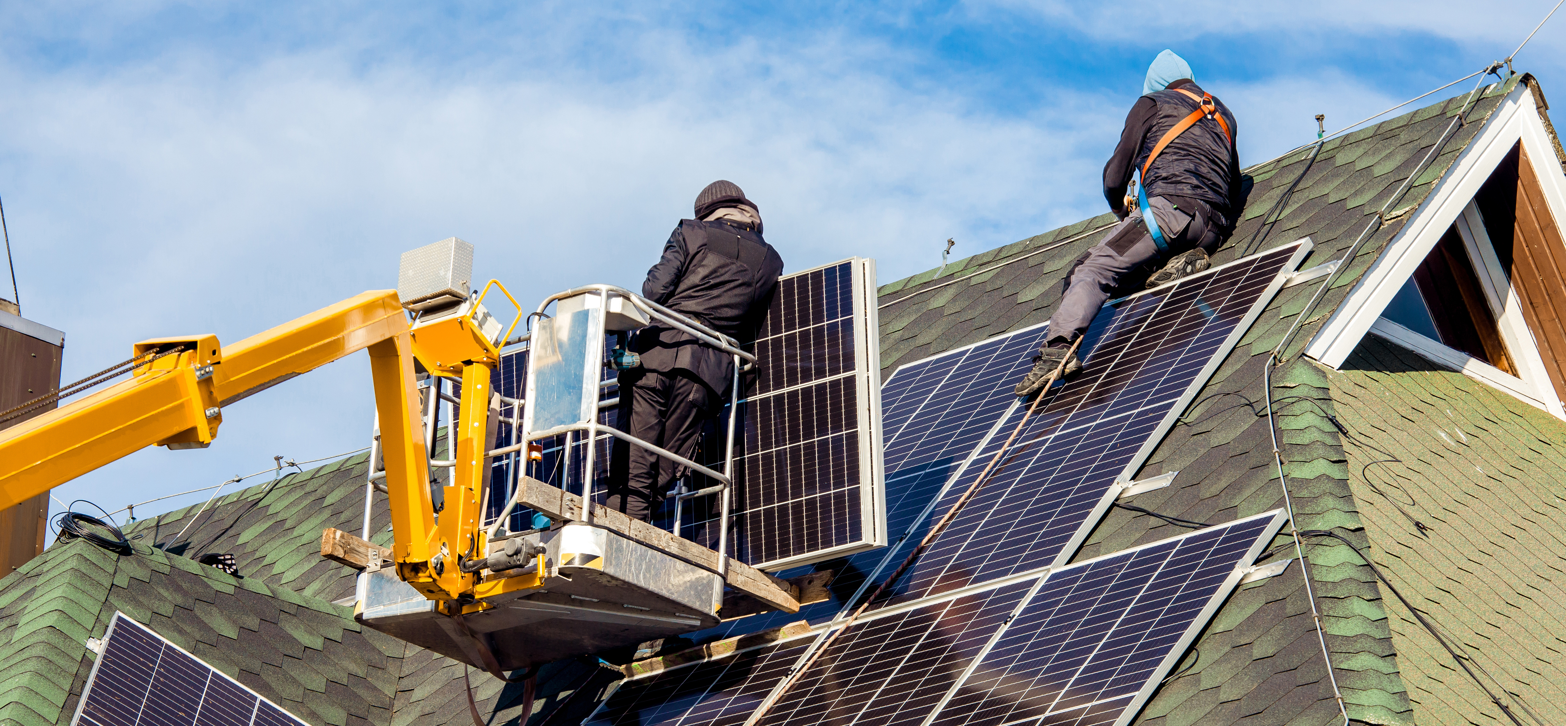 Two workers installing solar panels on a rooftop