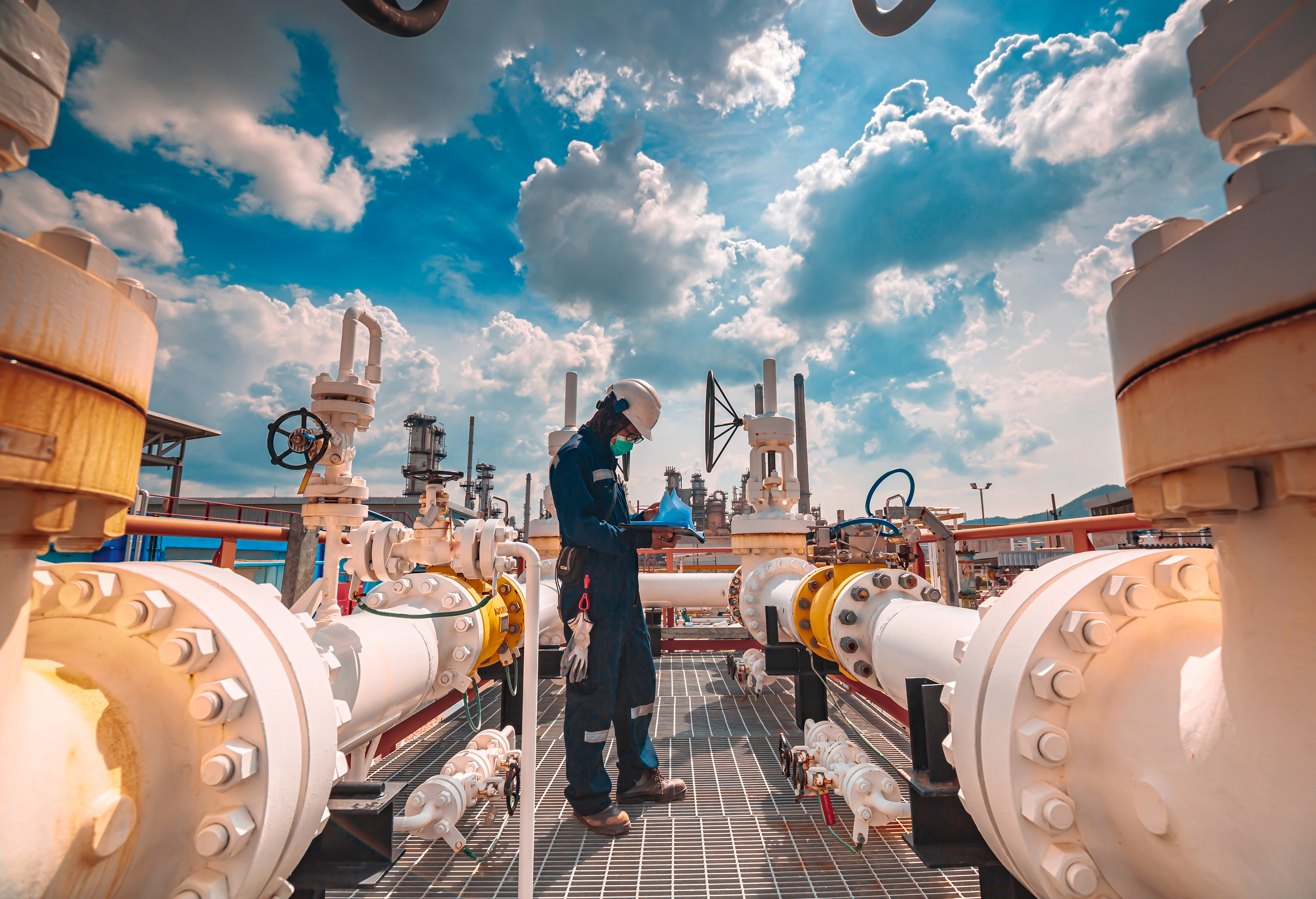 Engineer inspecting large-scale industrial refinery equipment