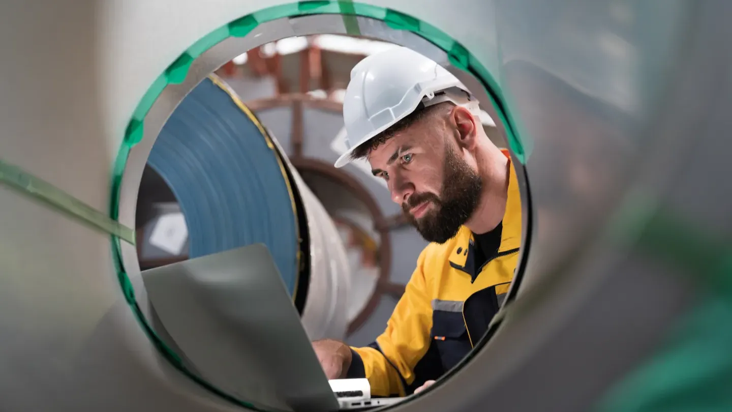 Engineer inspecting rolled steel inside an industrial facility