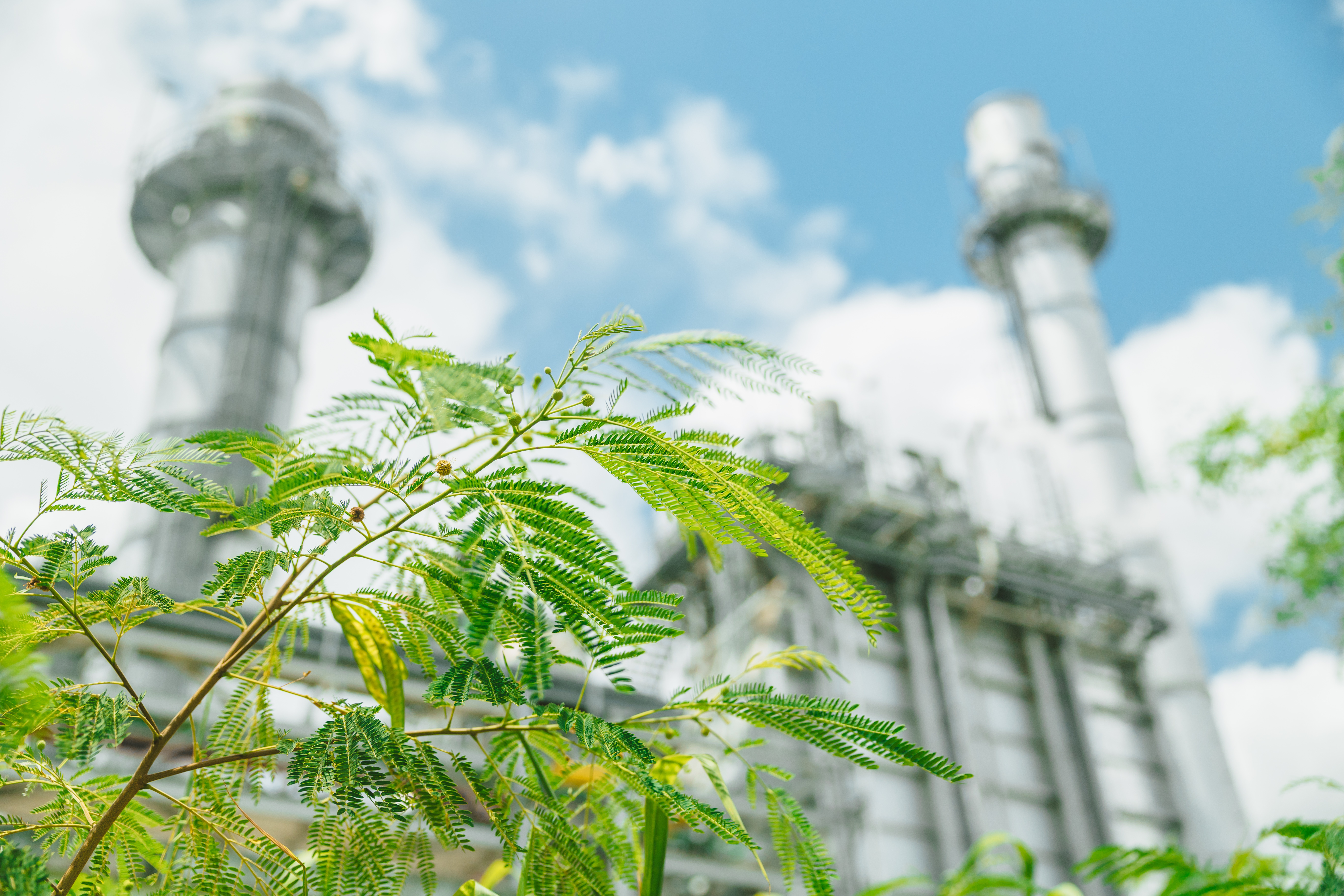 Industrial facility with emissions stacks surrounded by greenery