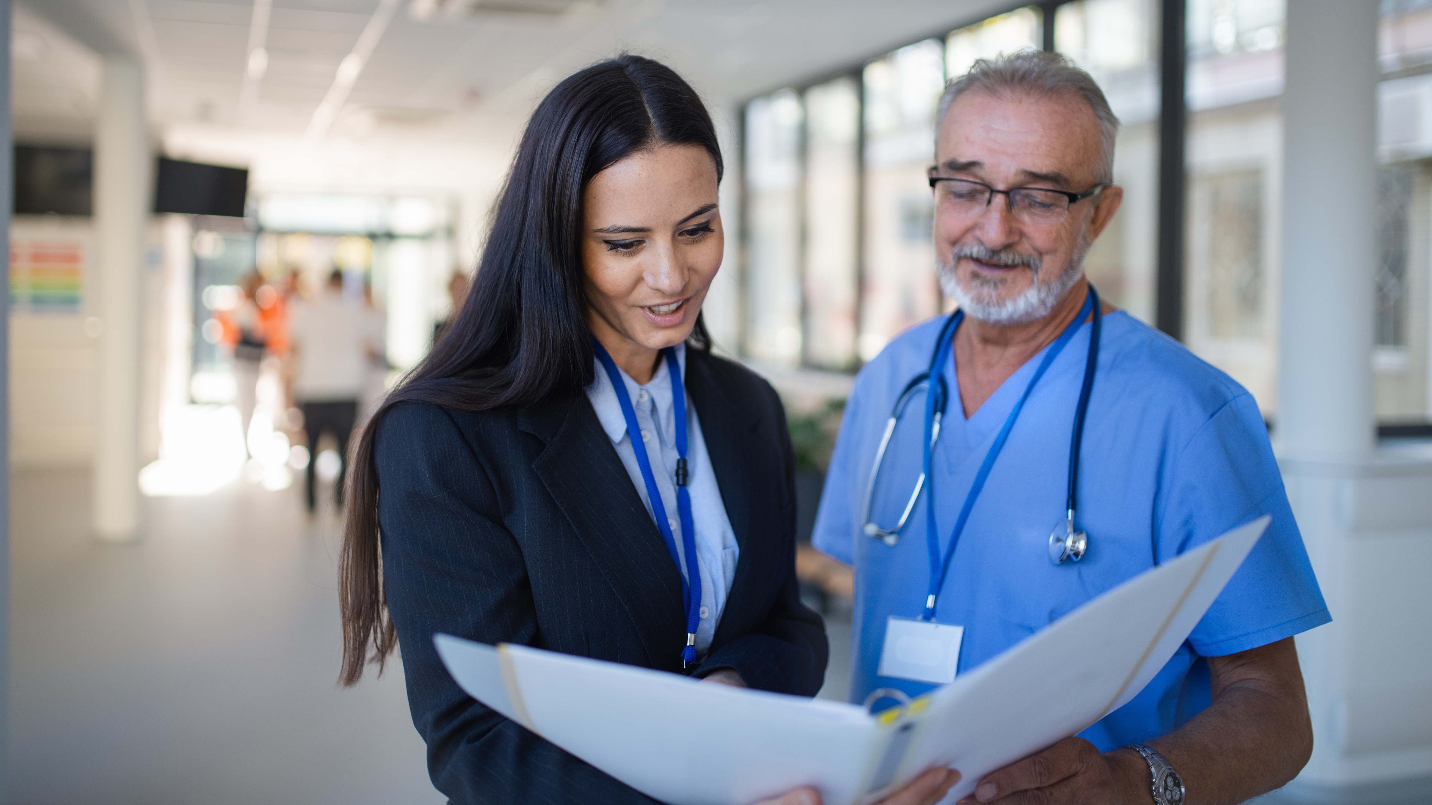A hospital administrator and a medical professional reviewing accreditation documents together, symbolizing partnership, quality assurance, and clinical excellence.