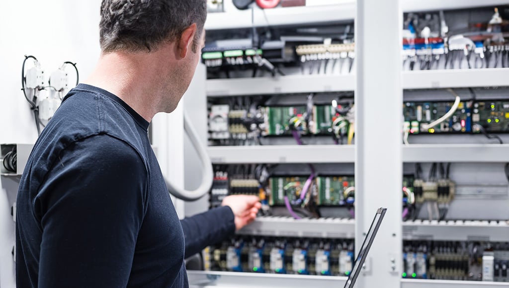 Electrician working on electronics cabinet