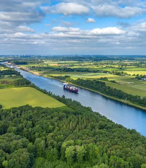 Vessel passing through canal in green landscape