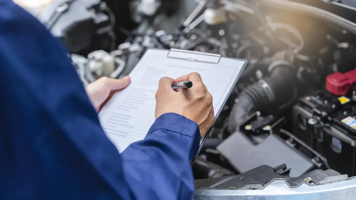 Engineer reviewing functional safety documentation beside a vehicle engine, illustrating ISO 26262 readiness assessment and pre-audit evaluation