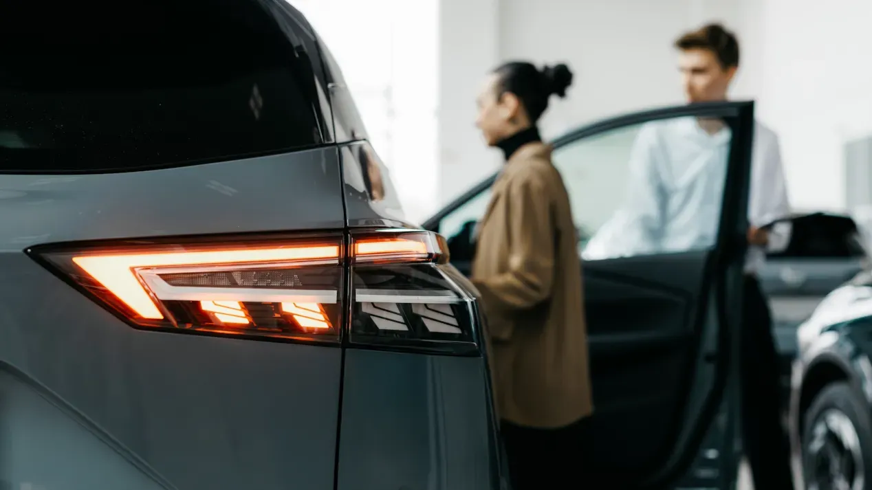 Person approaching a vehicle with illuminated rear lights, symbolising post-launch reliability performance and customer experience