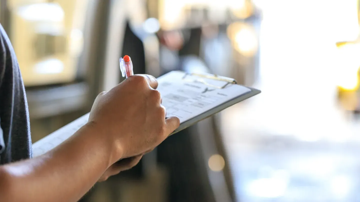 Assurance expert reviewing documentation and taking compliance notes inside an automotive production facility