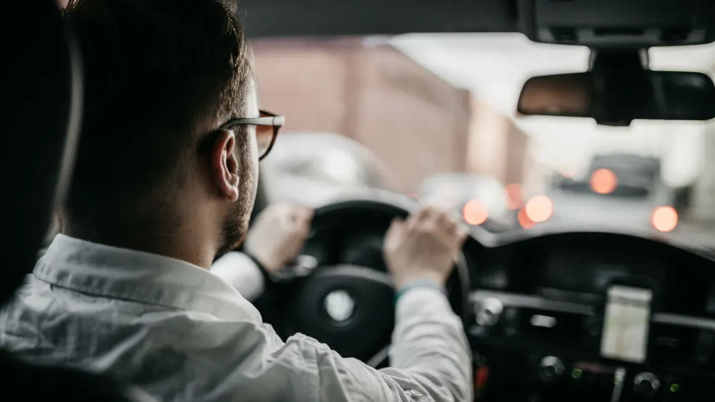 Driver reviewing vehicle dashboard and navigation display, representing visibility and control across automotive processes