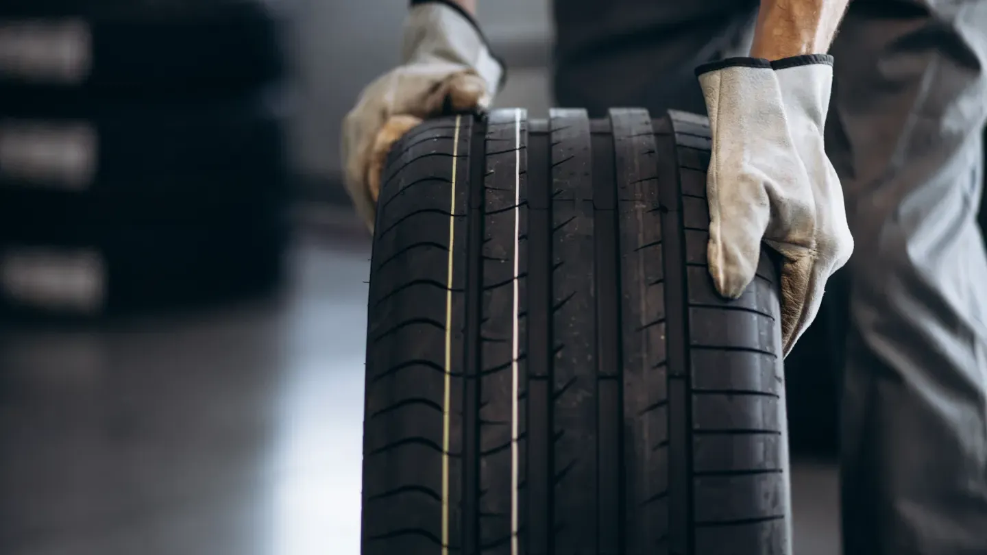 Technician holding a car tire during inspection, symbolising vehicle reliability testing and performance assessment