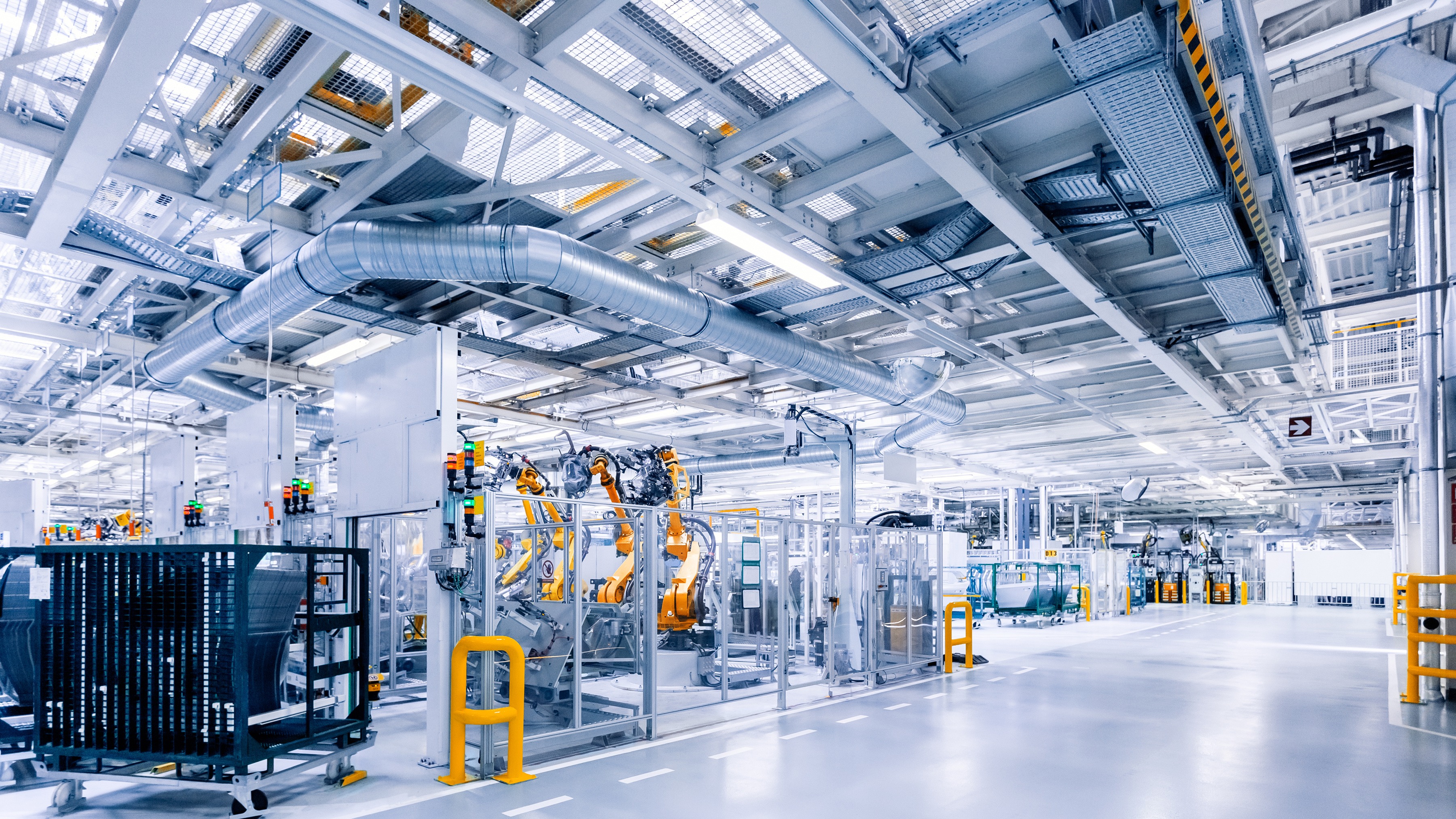 Modern automotive production hall with vehicle bodies, robots and test equipment, illustrating reliability and robustness testing in a real-world factory environment