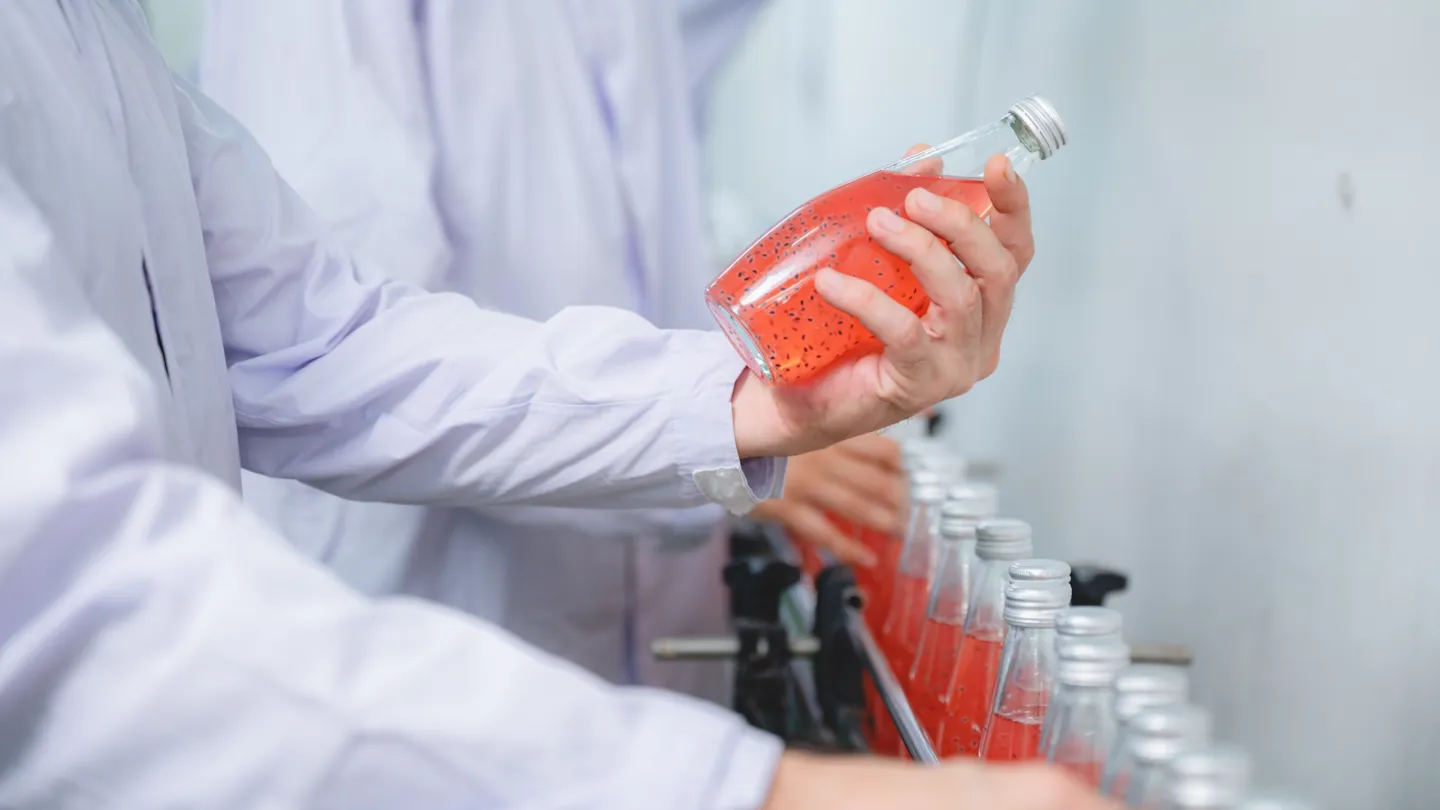 Worker wearing protective gloves handling packaged meat products, illustrating QHSE controls and hygiene practices