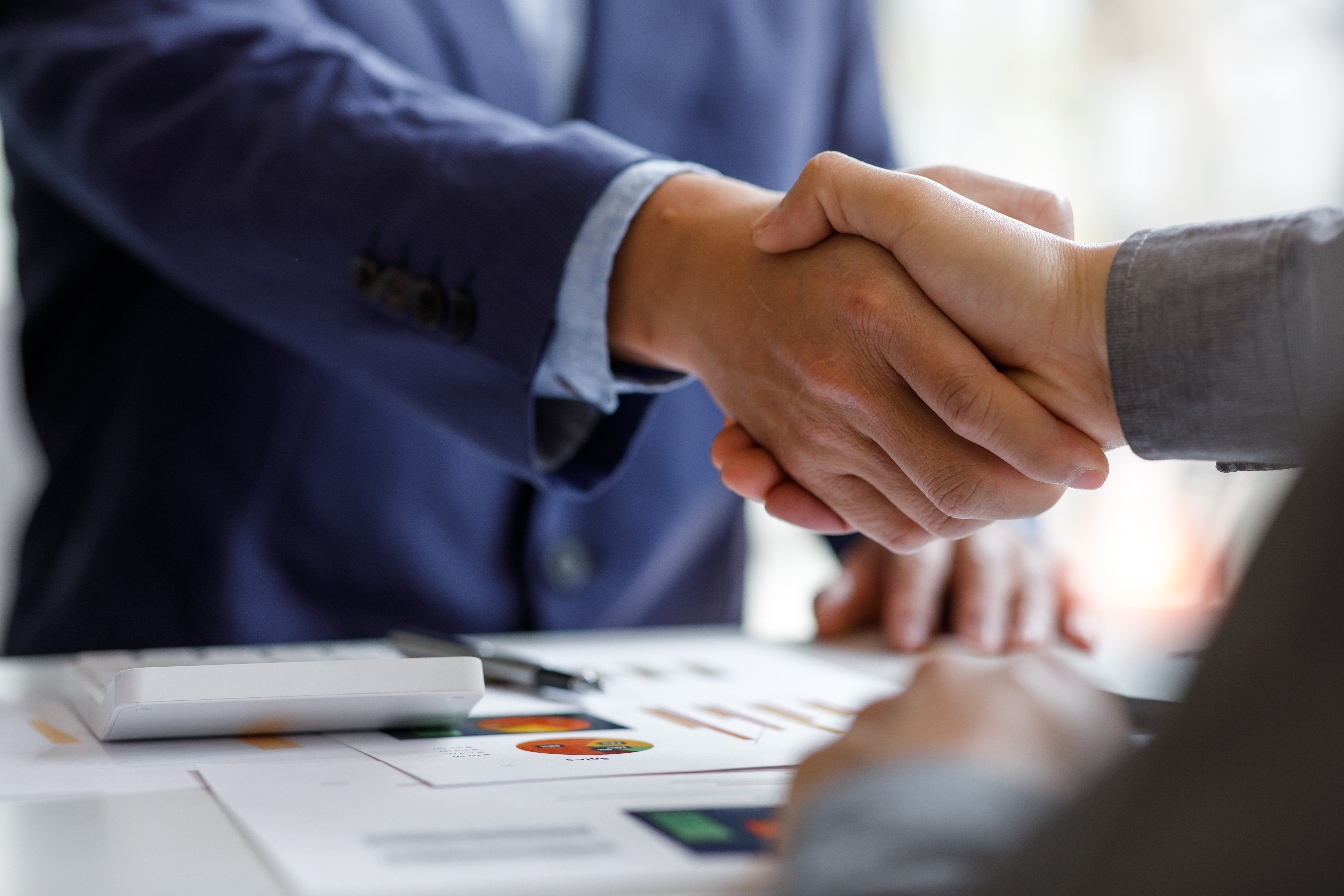 Close-up of two business professionals shaking hands during a compliance or social audit meeting, symbolising trust and ethical sourcing