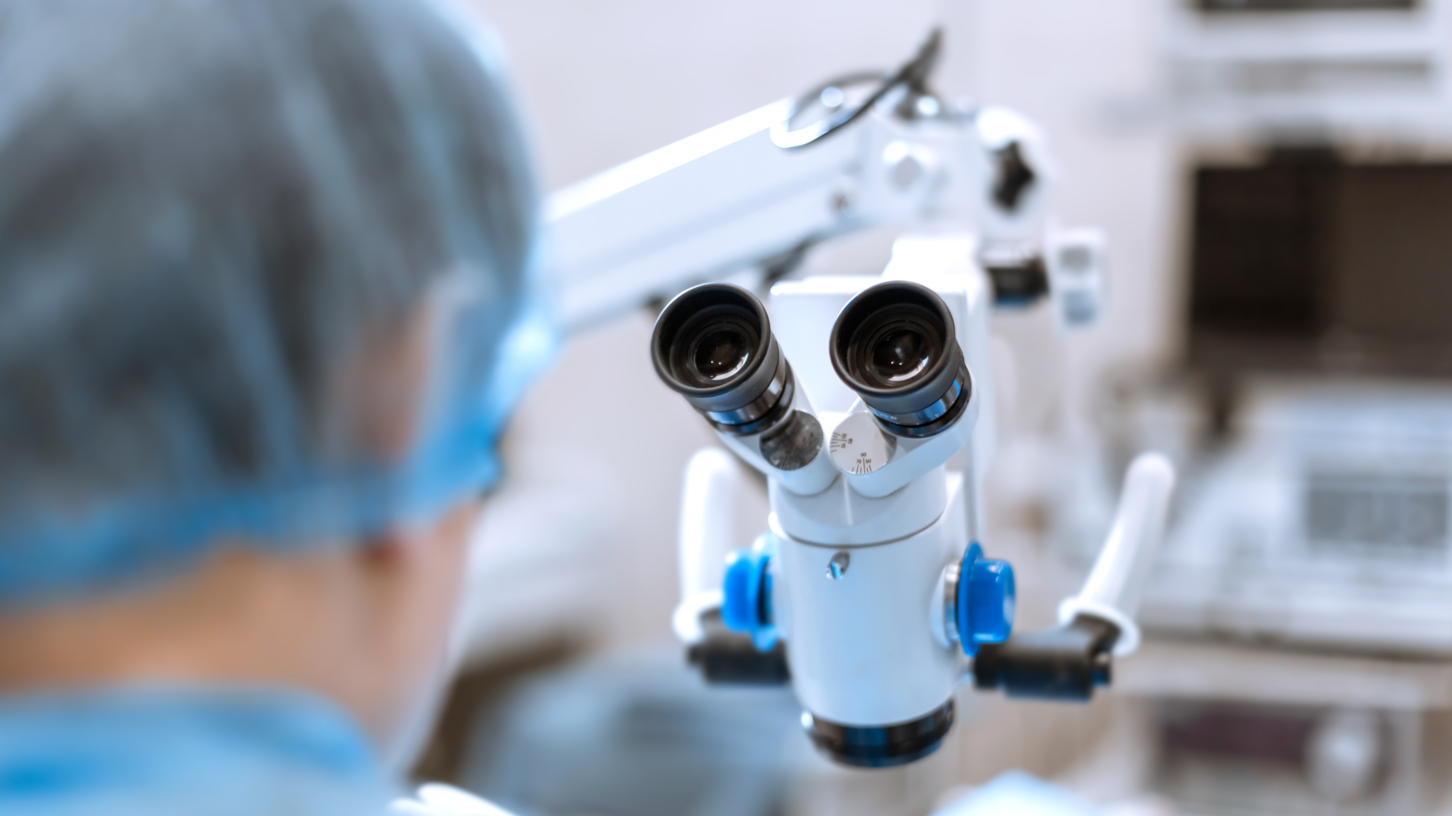 A healthcare professional using a surgical microscope, representing precision and clinical excellence in infection prevention and patient safety.