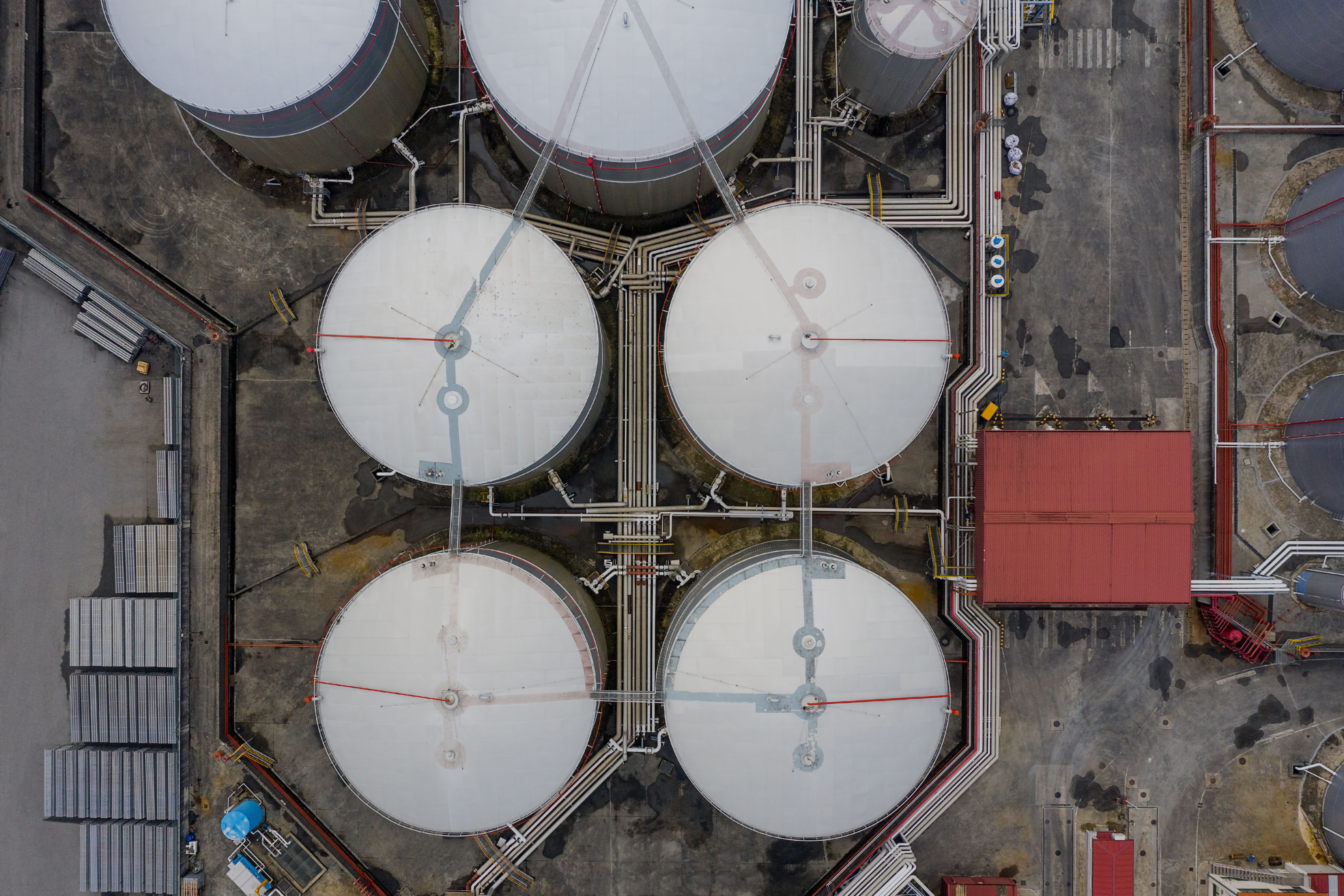 Aerial view of large industrial storage tanks with connecting pipework and access platforms, representing EX equipment installed in hazardous areas