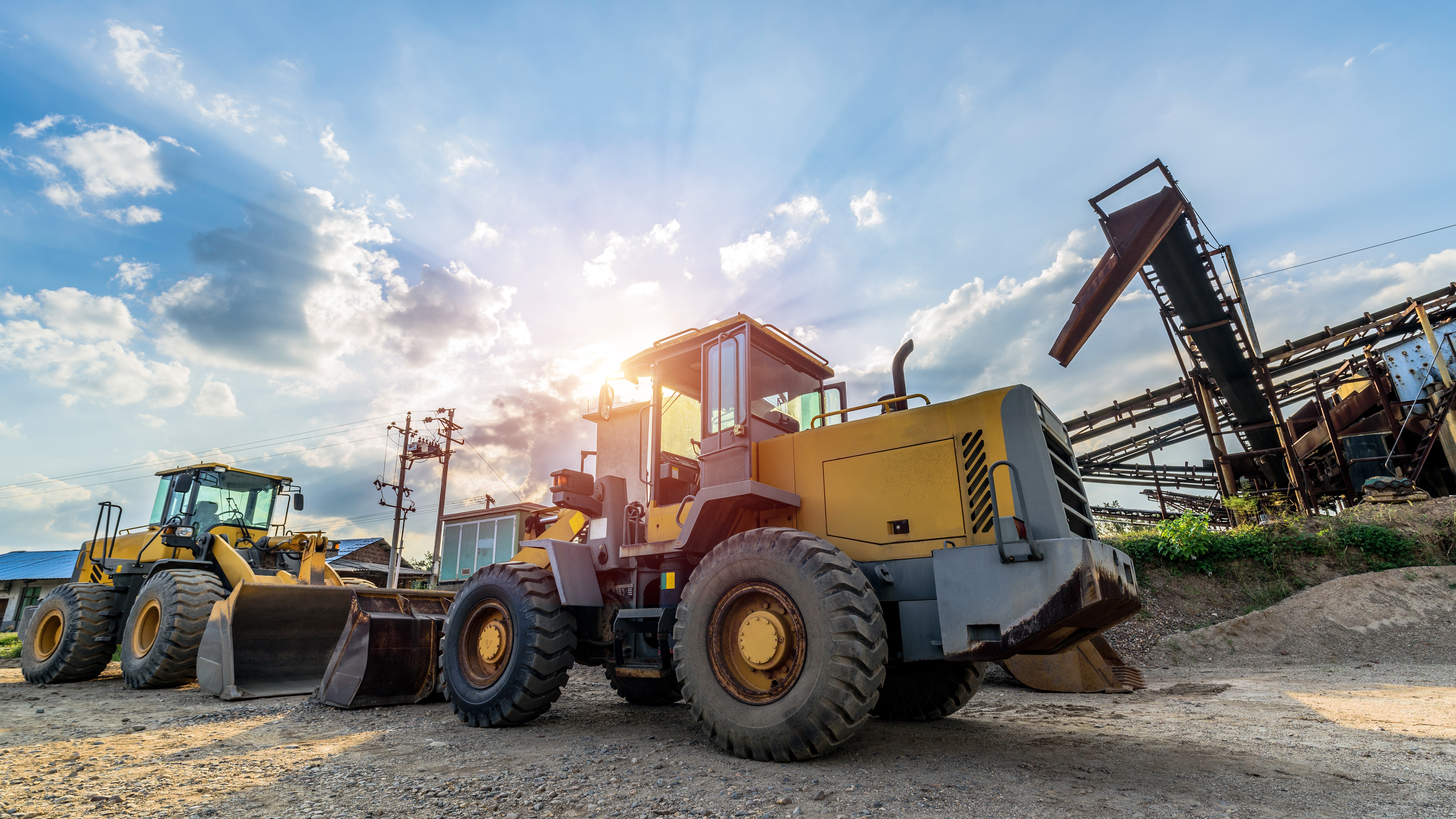 Yellow wheel loader and other construction machinery parked in a quarry yard at sunset, symbolizing heavy-duty equipment and materials traceability
