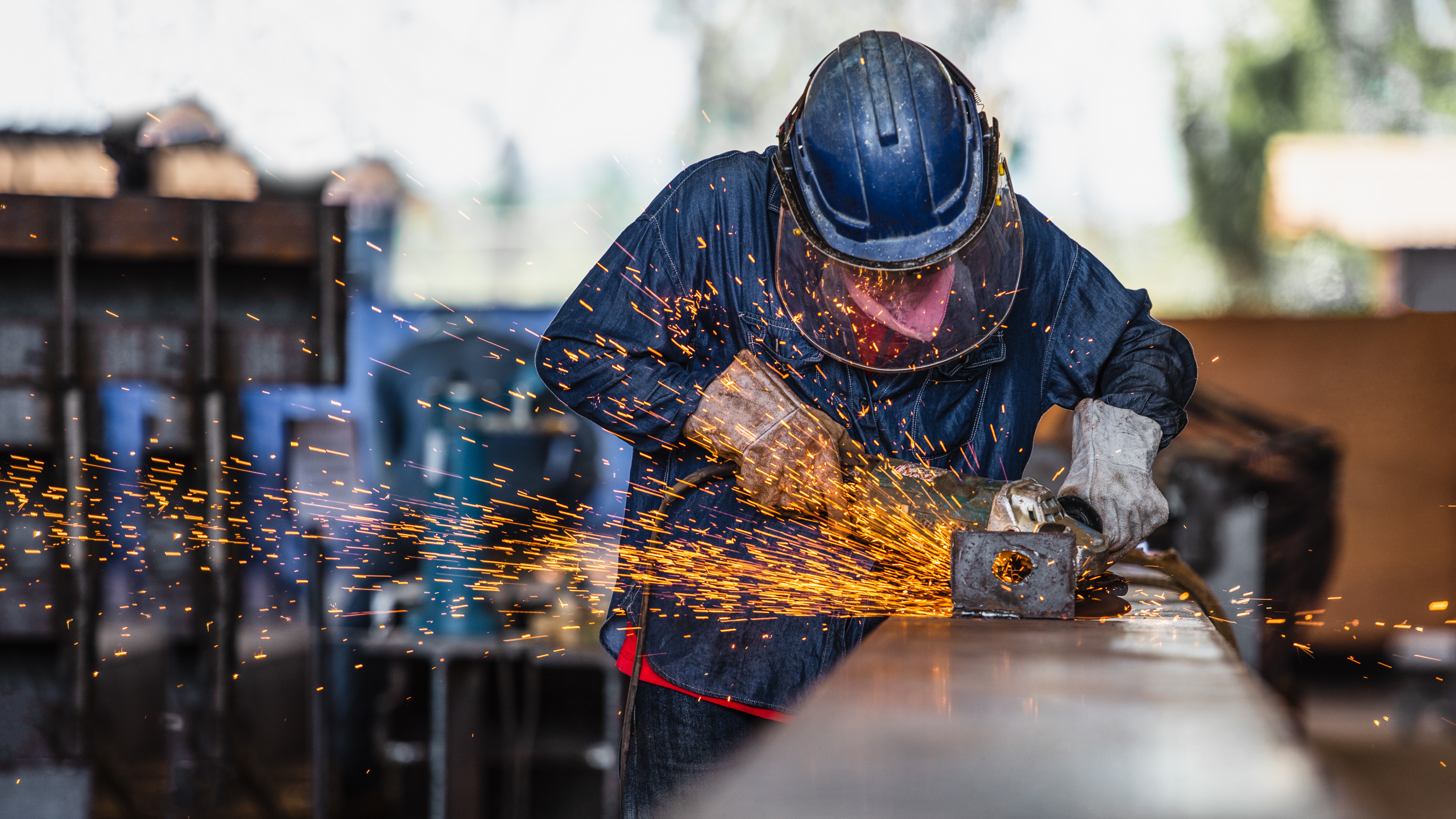 Close-up of an automated cutting or welding machine producing bright sparks over a metal sheet, representing welding and fabrication processes in an industrial workshop