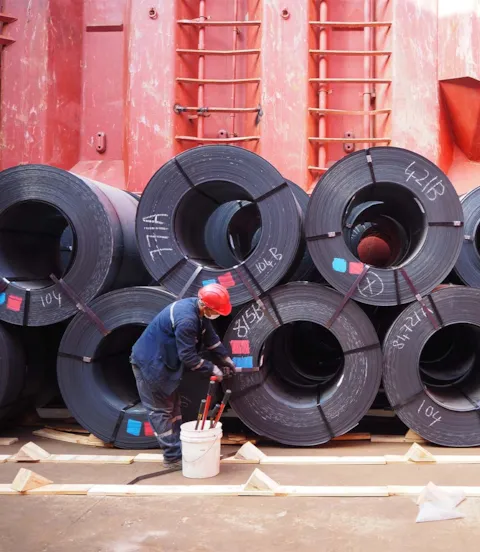 Worker fastening steel coils in cargo hold