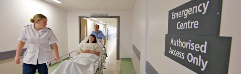Medical staff wheeling patient through hospital corridor