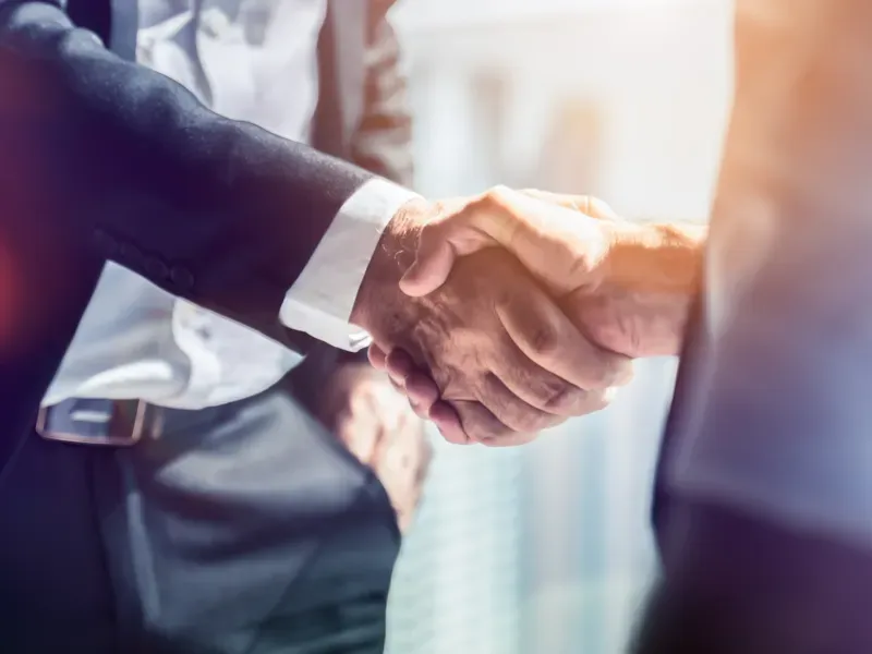Business professionals shaking hands during a sustainability meeting, symbolizing trusted advisory support in sustainable finance