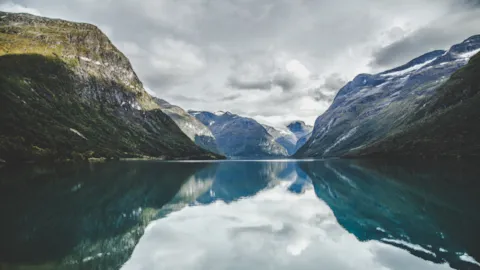 Mountain fjord ecosystem landscape with calm water reflecting surrounding environment