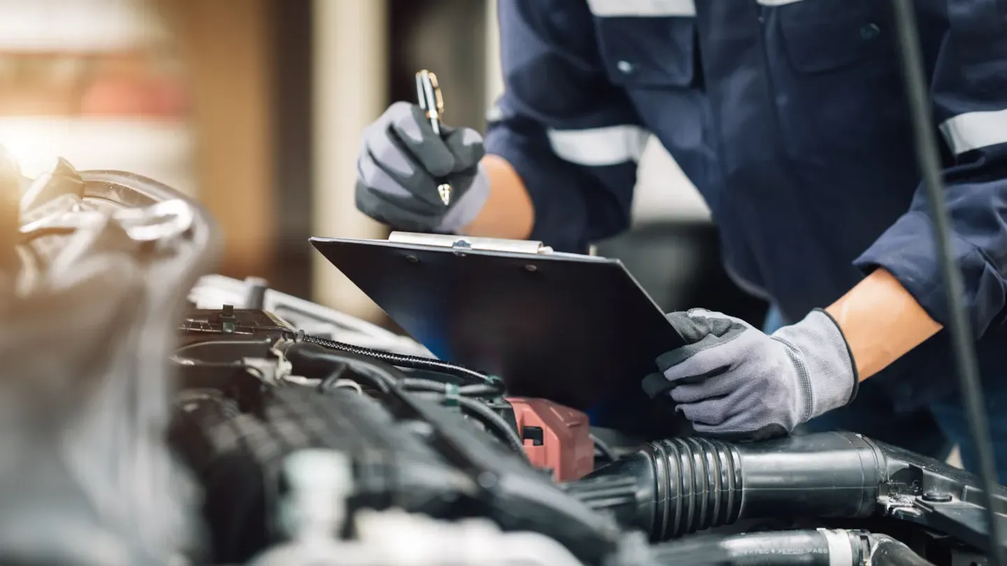 Automotive technician using diagnostic tools to assess vehicle components, representing structured failure analysis and FMEA evaluation.