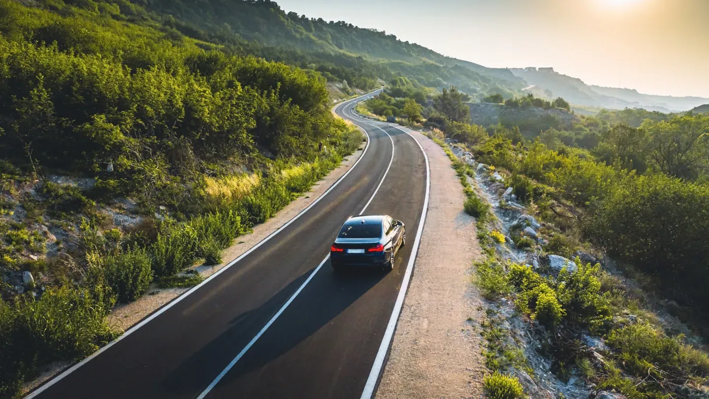 Car driving along a mountain road at sunset, representing improved capability and process outcomes from ASPICE training