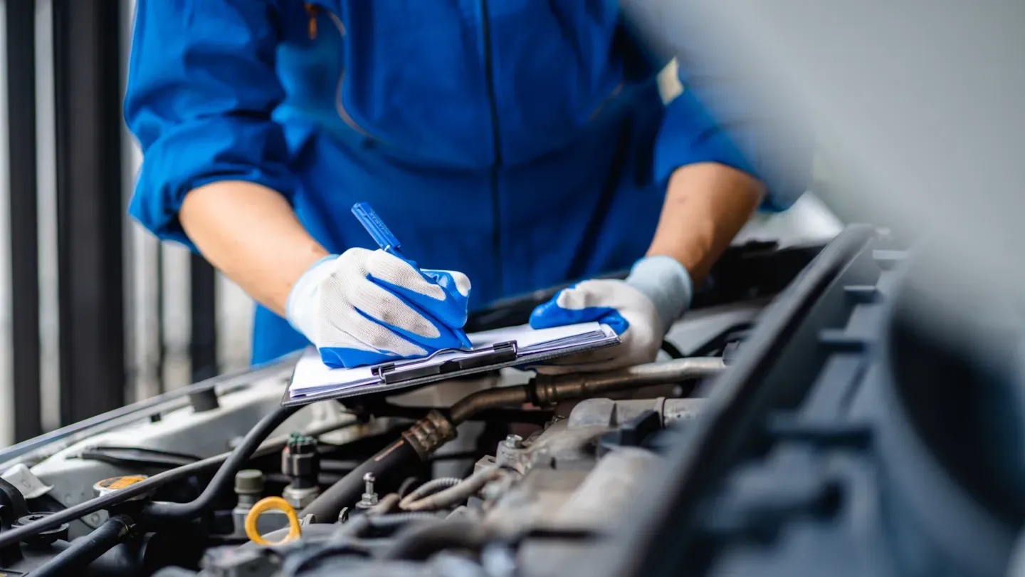 Automotive technician performing hands-on engine work to support data-driven continuous improvement