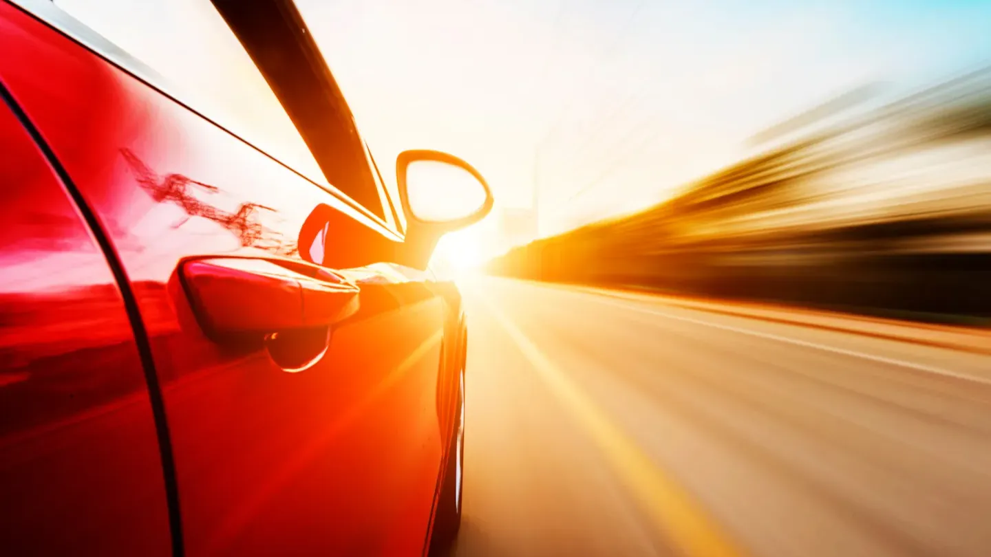 Driver’s hand on the steering wheel at sunrise, symbolizing improved safety performance and enhanced compliance across the development lifecycle