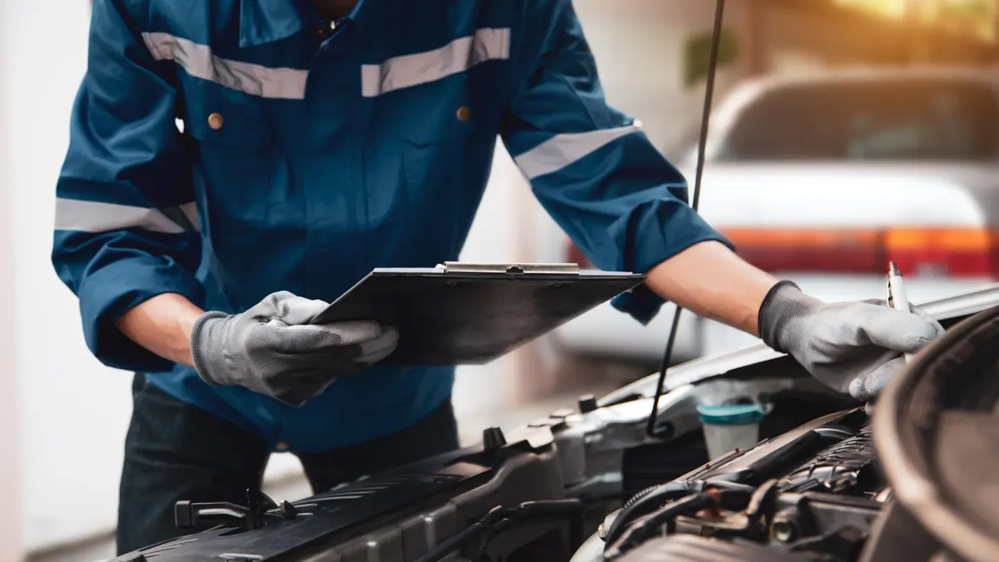 Automotive technician inspecting a vehicle’s engine components, representing safety diagnostics and reliability assessment